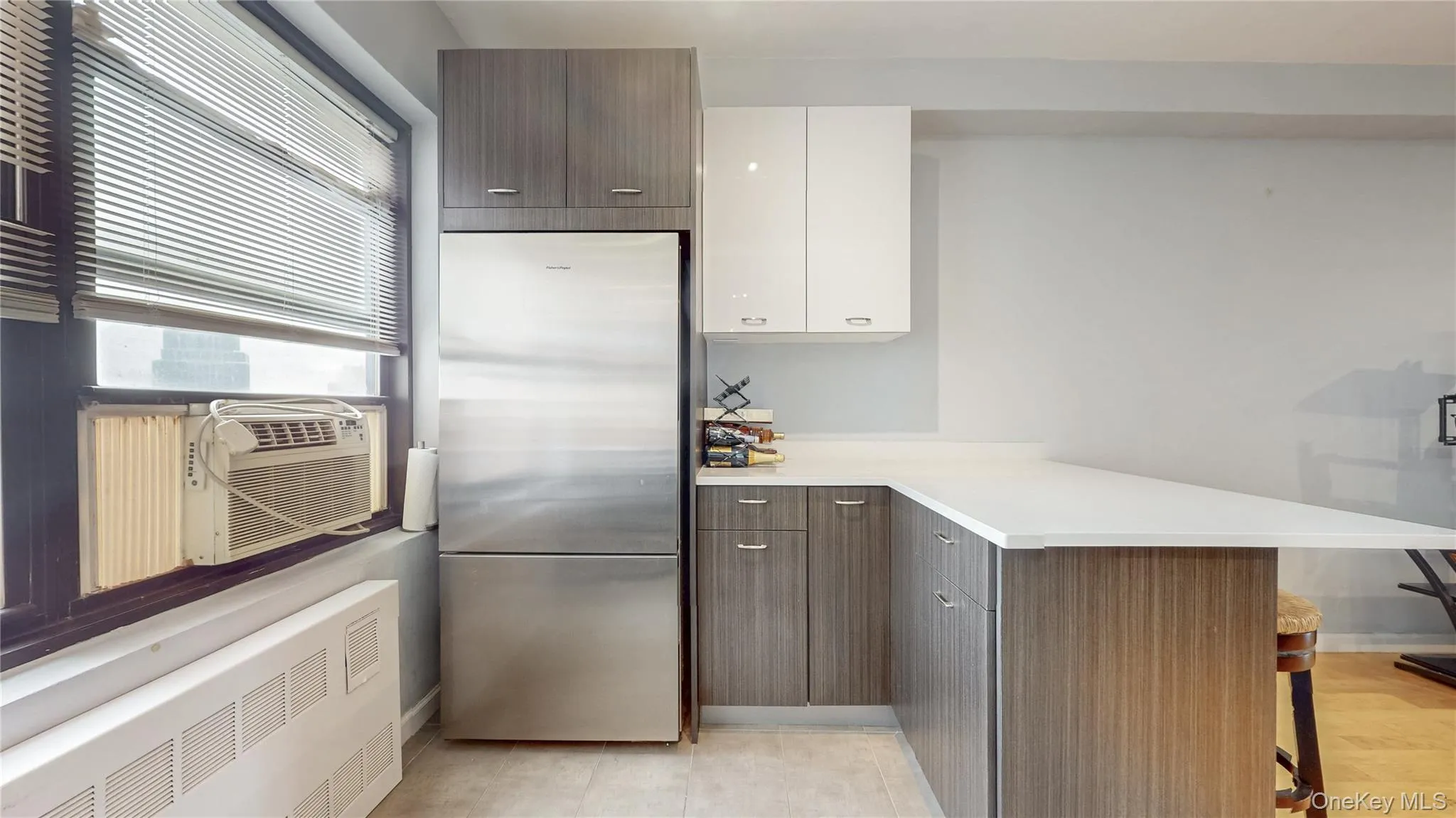 Kitchen with radiator, stainless steel refrigerator, a breakfast bar, a peninsula, and white cabinets Kitchen with radiator, stainless steel refrigerator, a breakfast bar, a peninsula, and white cabinets