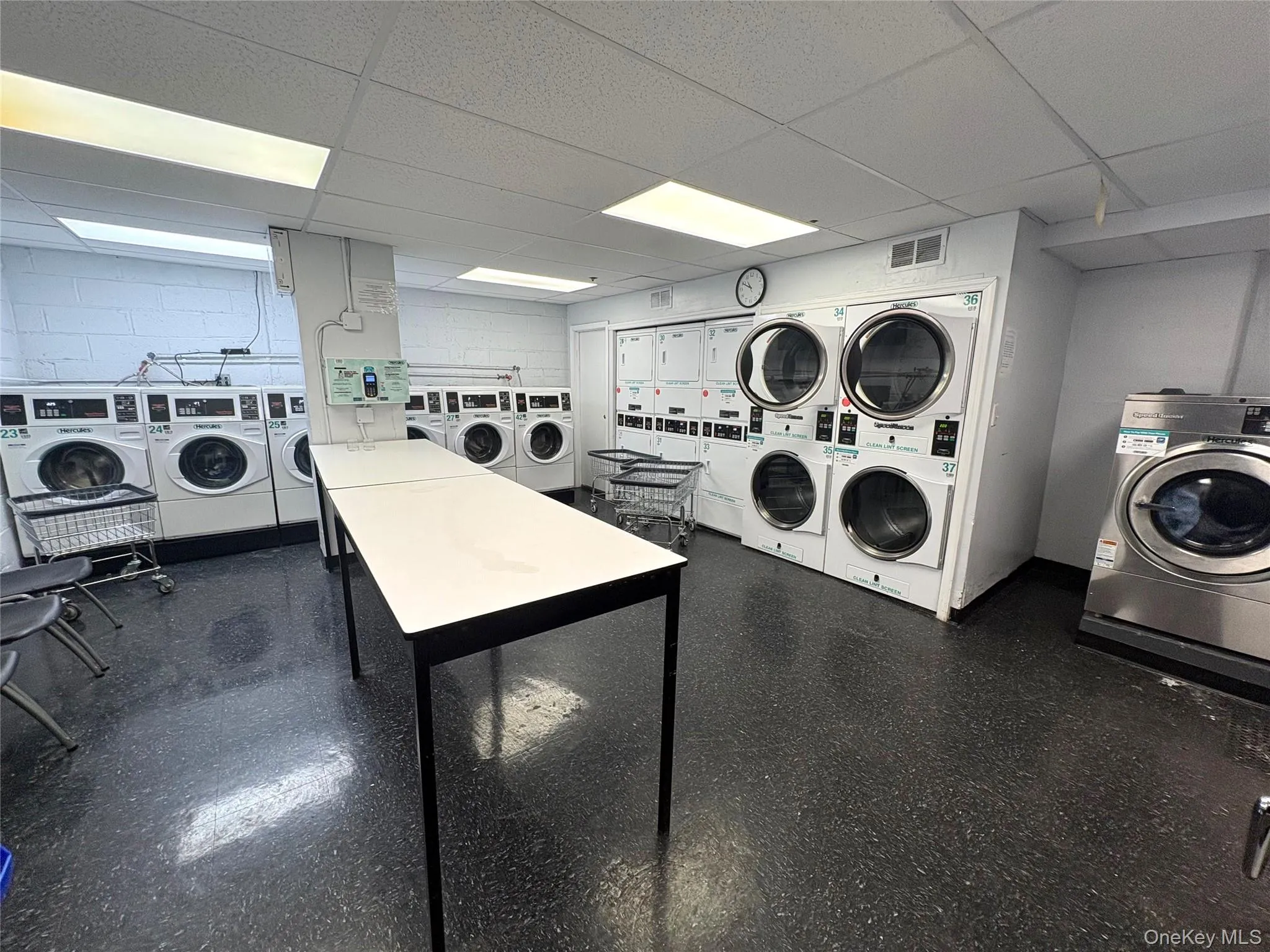 Communal laundry room featuring a drop ceiling and washing machine and clothes dryer Communal laundry room featuring a drop ceiling and washing machine and clothes dryer