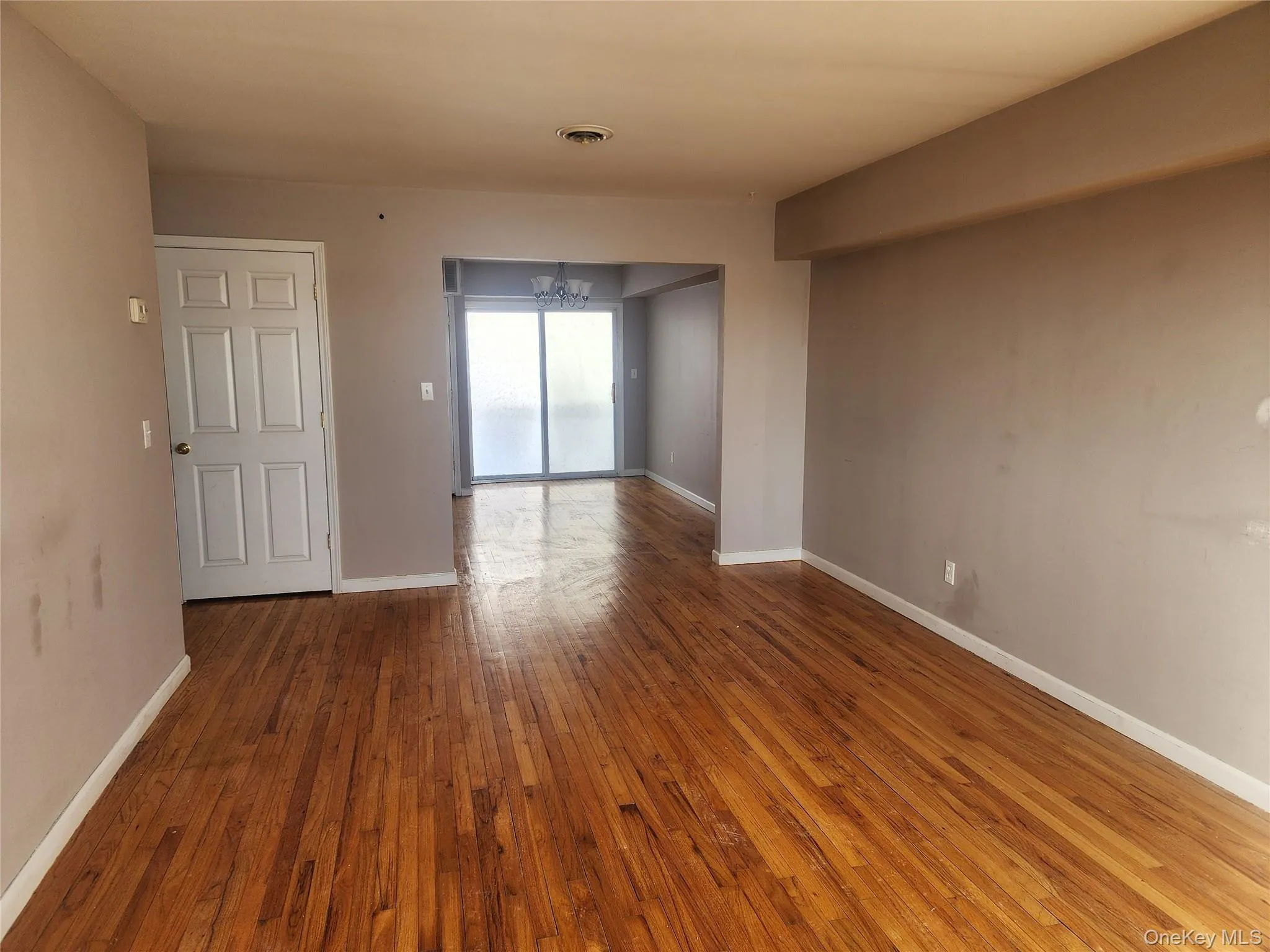 Empty room with a chandelier and hardwood / wood-style floors Empty room with a chandelier and hardwood / wood-style floors