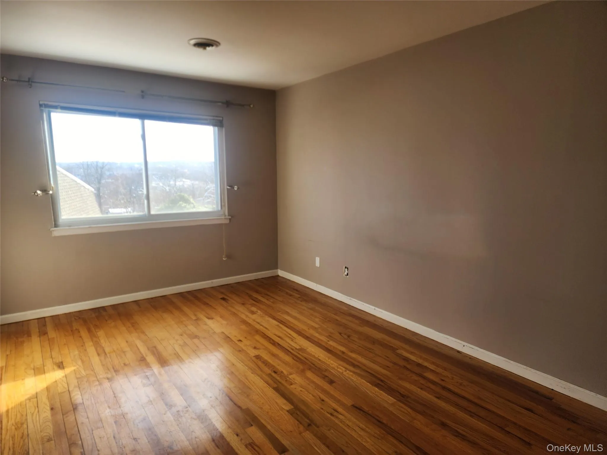Spare room featuring baseboards and hardwood / wood-style floors Spare room featuring baseboards and hardwood / wood-style floors