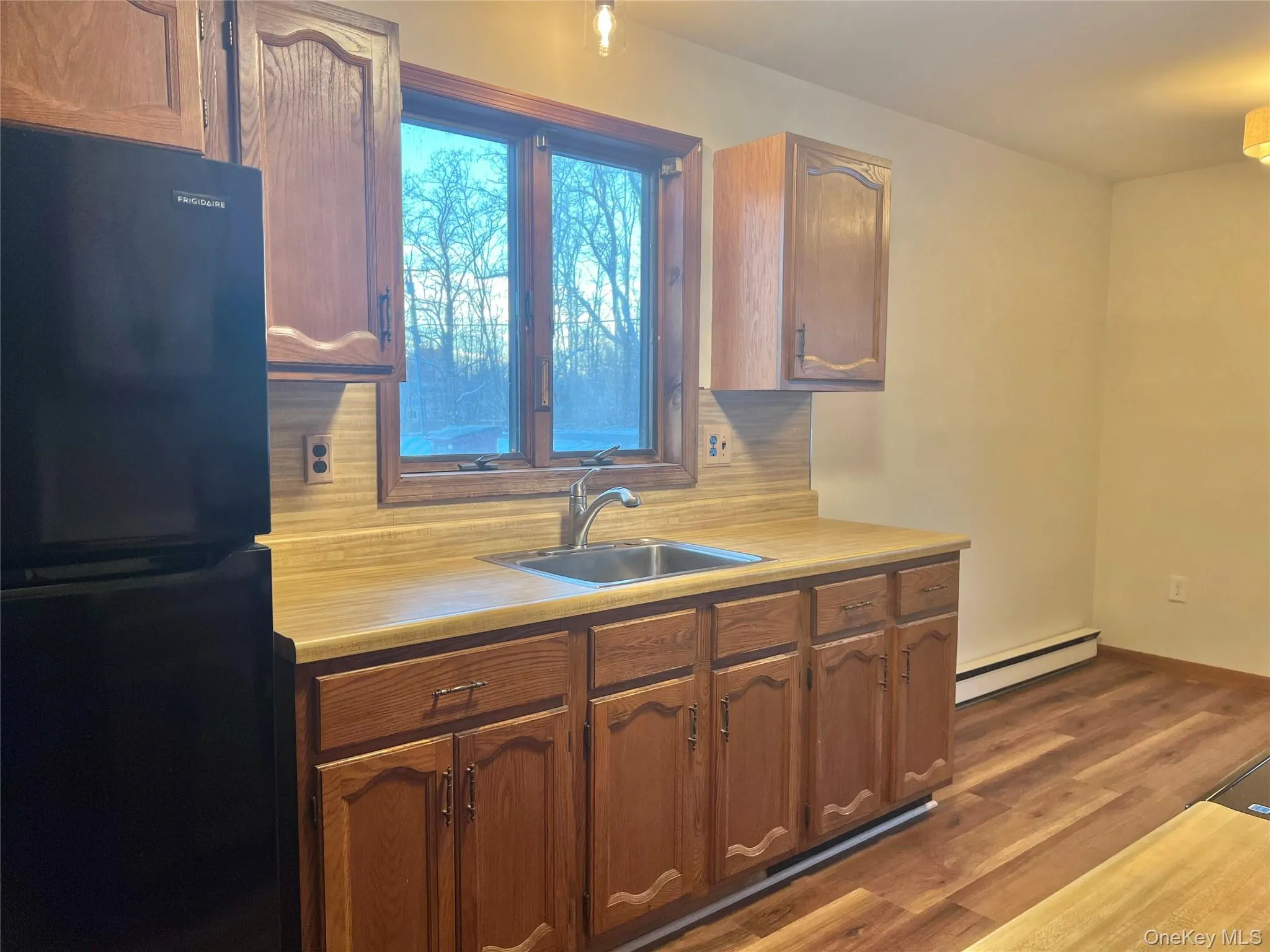 Kitchen featuring freestanding refrigerator, light countertops, tasteful backsplash, and dark wood finished floors Kitchen featuring freestanding refrigerator, light countertops, tasteful backsplash, and dark wood finished floors
