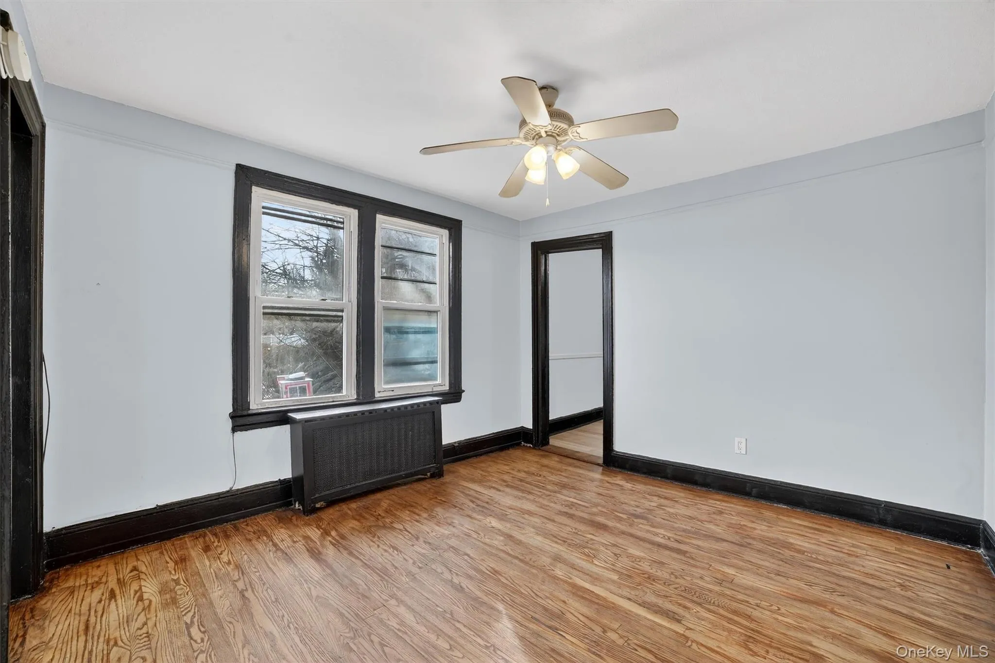 Spare room featuring radiator, wood finished floors, and a ceiling fan Spare room featuring radiator, wood finished floors, and a ceiling fan