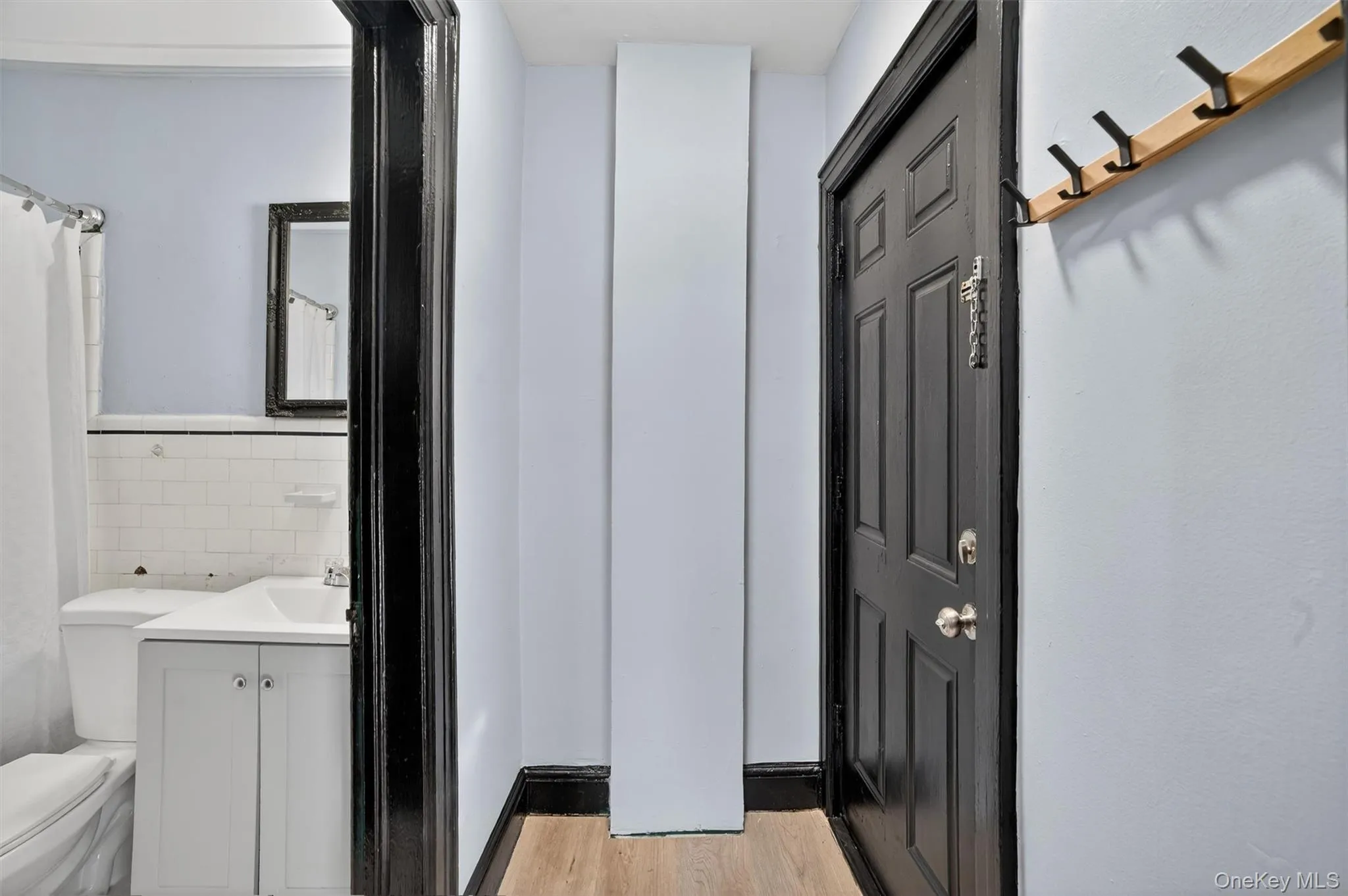 Bathroom featuring vanity, light wood finished floors, a shower with shower curtain, and tile walls Bathroom featuring vanity, light wood finished floors, a shower with shower curtain, and tile walls