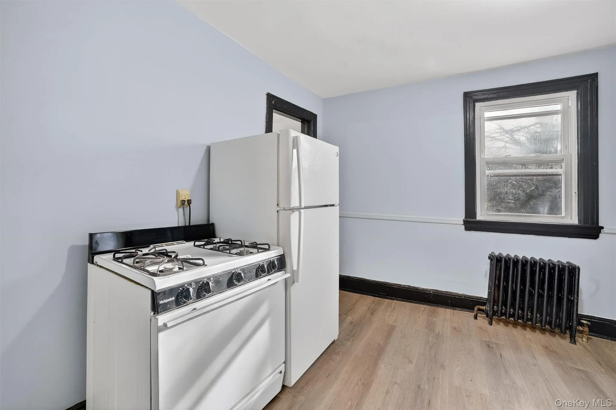 Kitchen with white gas range oven, radiator, and light wood-type flooring Kitchen with white gas range oven, radiator, and light wood-type flooring