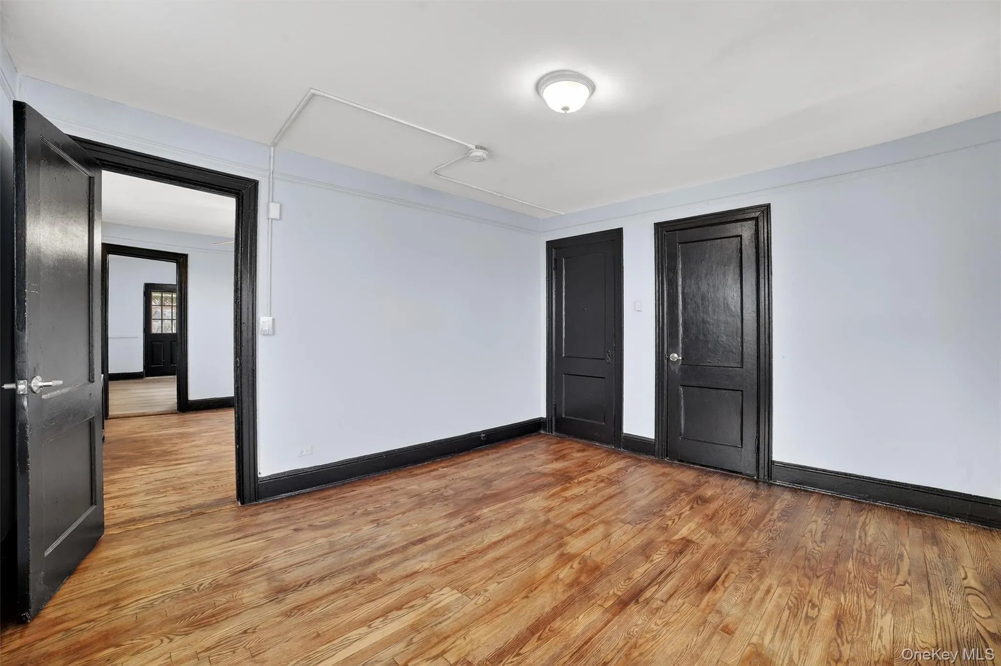 Unfurnished bedroom with light wood-style flooring and two closets Unfurnished bedroom with light wood-style flooring and two closets