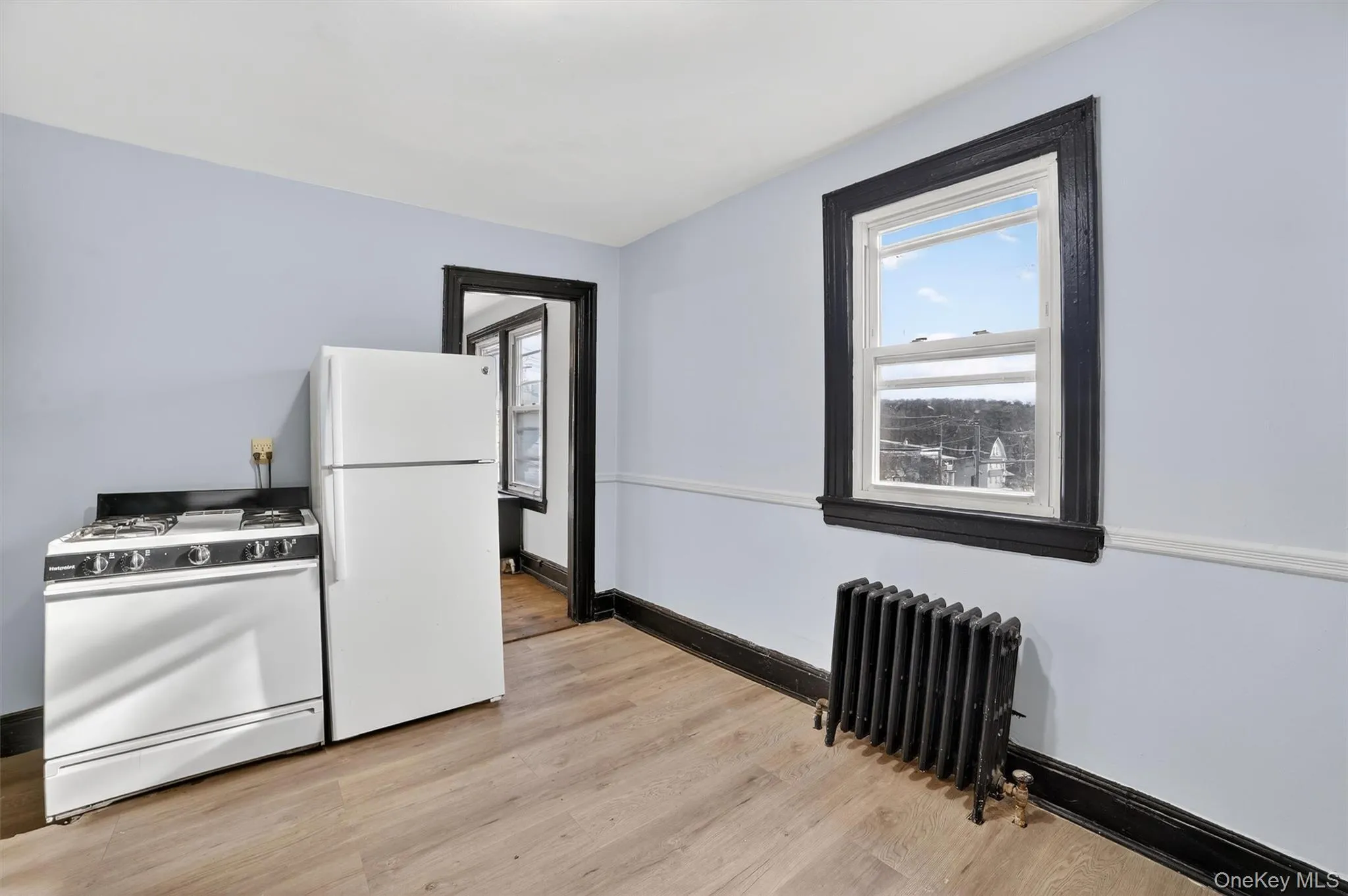 Kitchen featuring white appliances, radiator heating unit, healthy amount of natural light, and light wood-style floors Kitchen featuring white appliances, radiator heating unit, healthy amount of natural light, and light wood-style floors