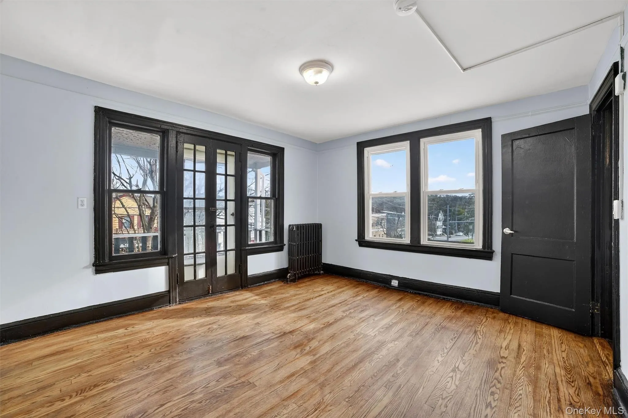 Empty room with radiator heating unit and light wood-style floors Empty room with radiator heating unit and light wood-style floors