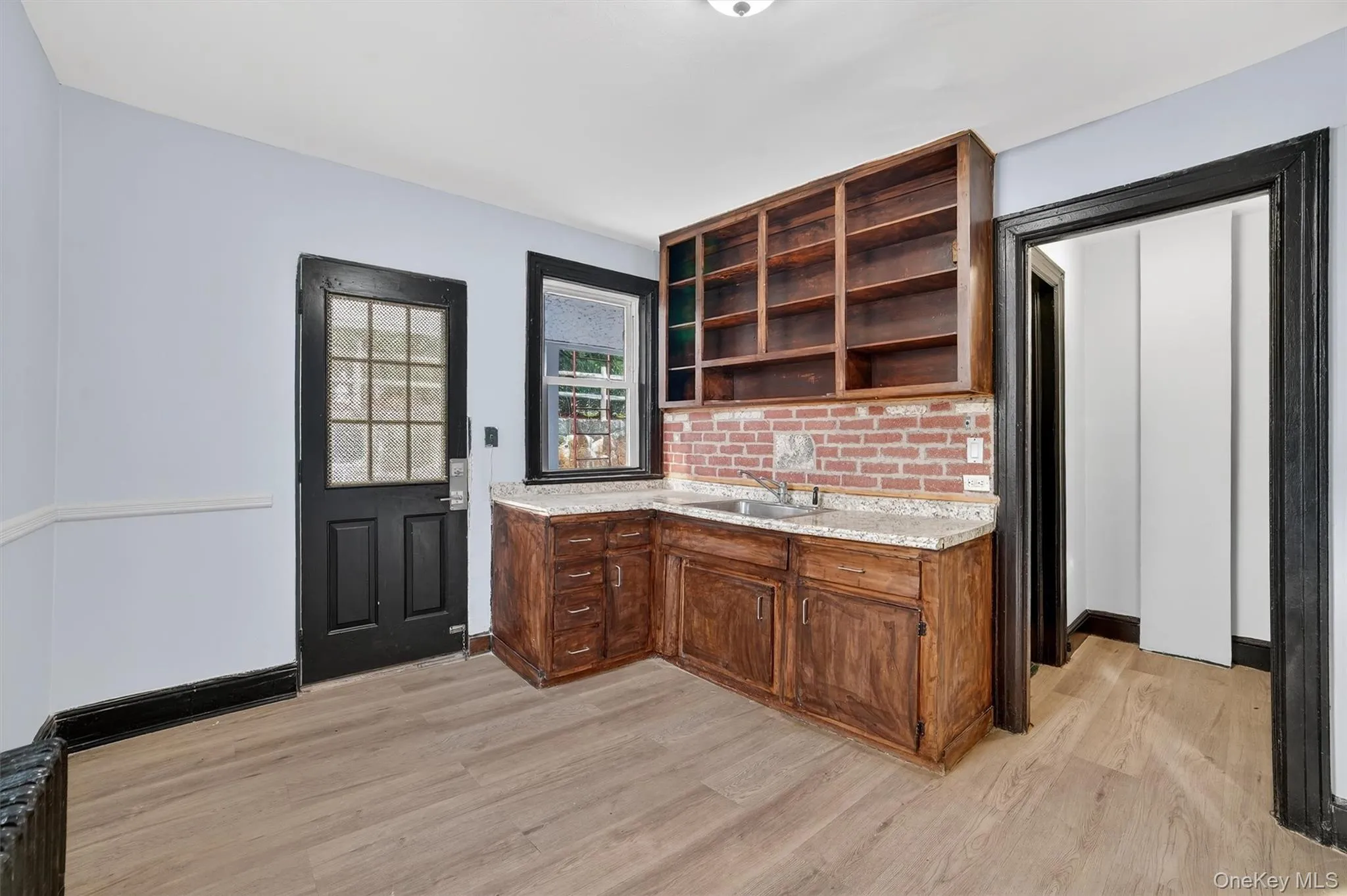 Kitchen with open shelves, light stone counters, and light wood-style floors Kitchen with open shelves, light stone counters, and light wood-style floors