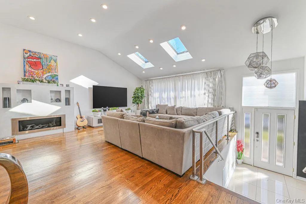Living area with a skylight, light wood finished floors, recessed lighting, and high vaulted ceiling Living area with a skylight, light wood finished floors, recessed lighting, and high vaulted ceiling