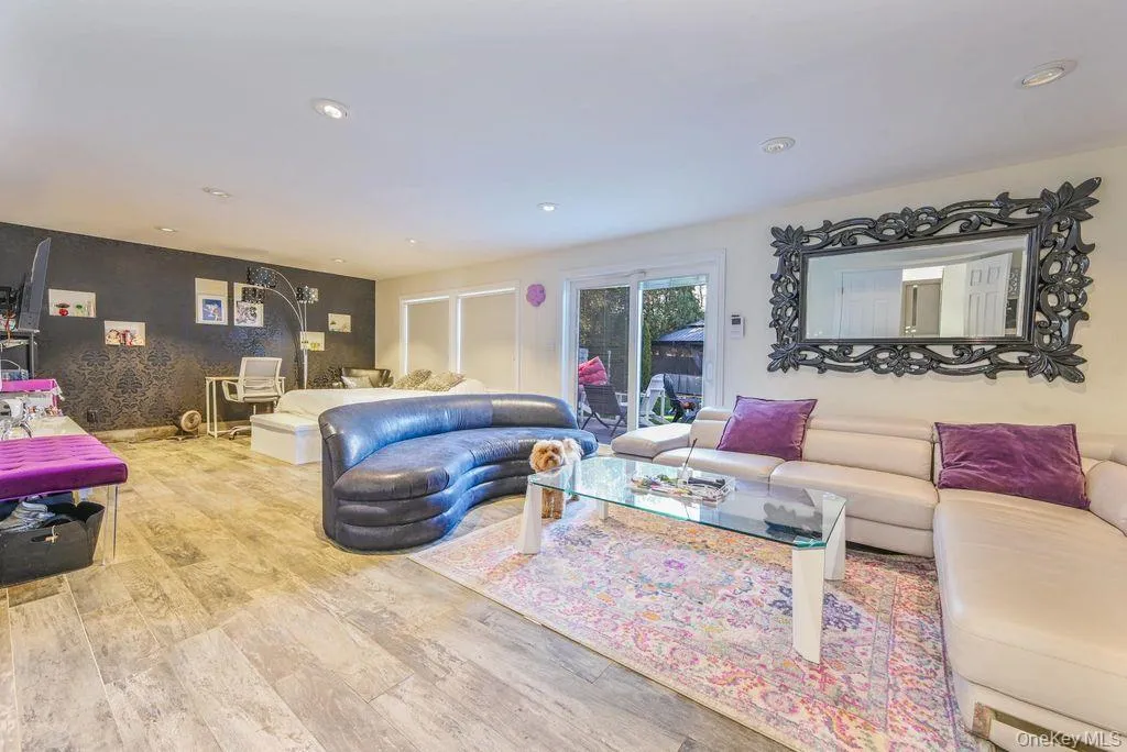 Living area featuring wood finished floors, recessed lighting, and an accent wall Living area featuring wood finished floors, recessed lighting, and an accent wall