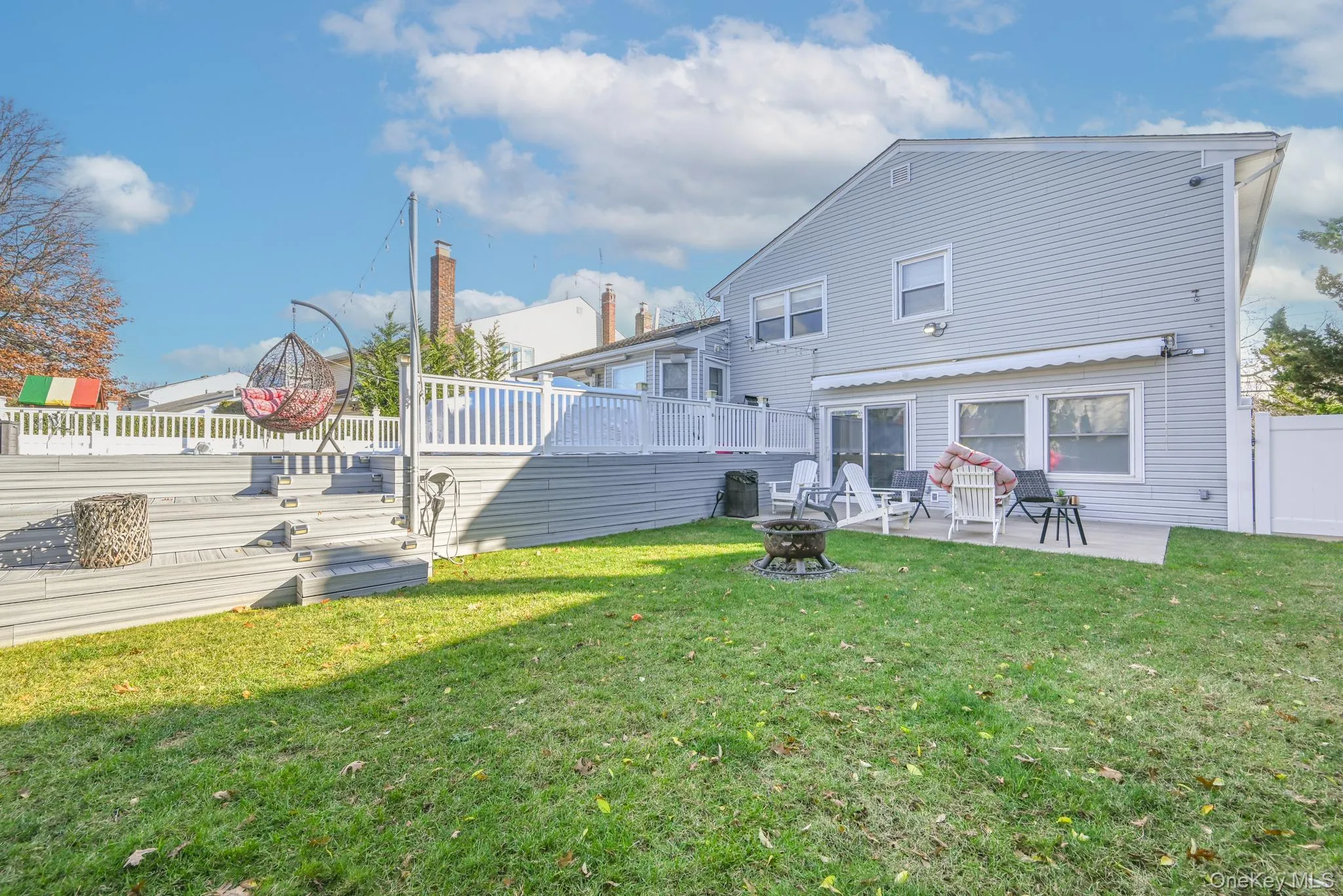 Back of house featuring a fenced backyard, an outdoor fire pit, a wooden deck, and a patio area Back of house featuring a fenced backyard, an outdoor fire pit, a wooden deck, and a patio area