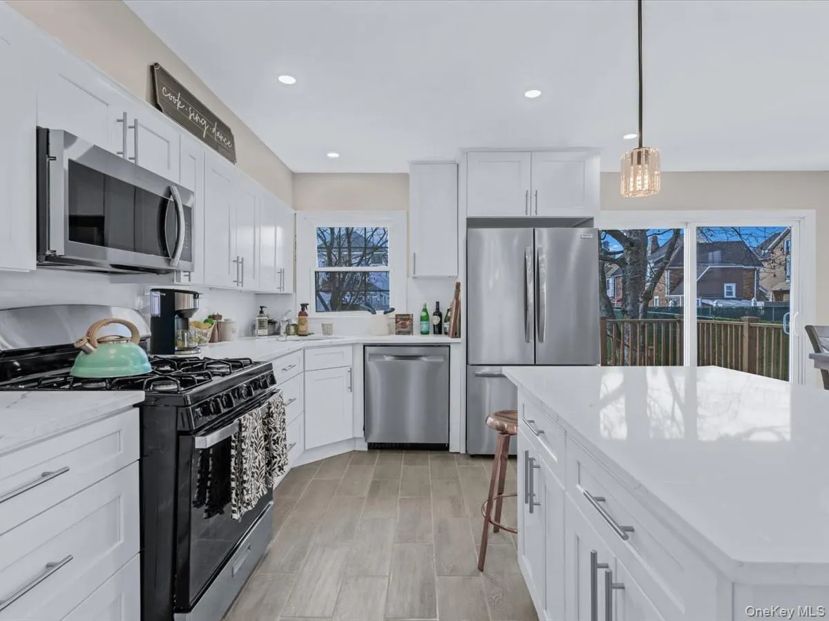 Kitchen with stainless steel appliances, white cabinets, light stone countertops, pendant lighting, and recessed lighting Kitchen with stainless steel appliances, white cabinets, light stone countertops, pendant lighting, and recessed lighting