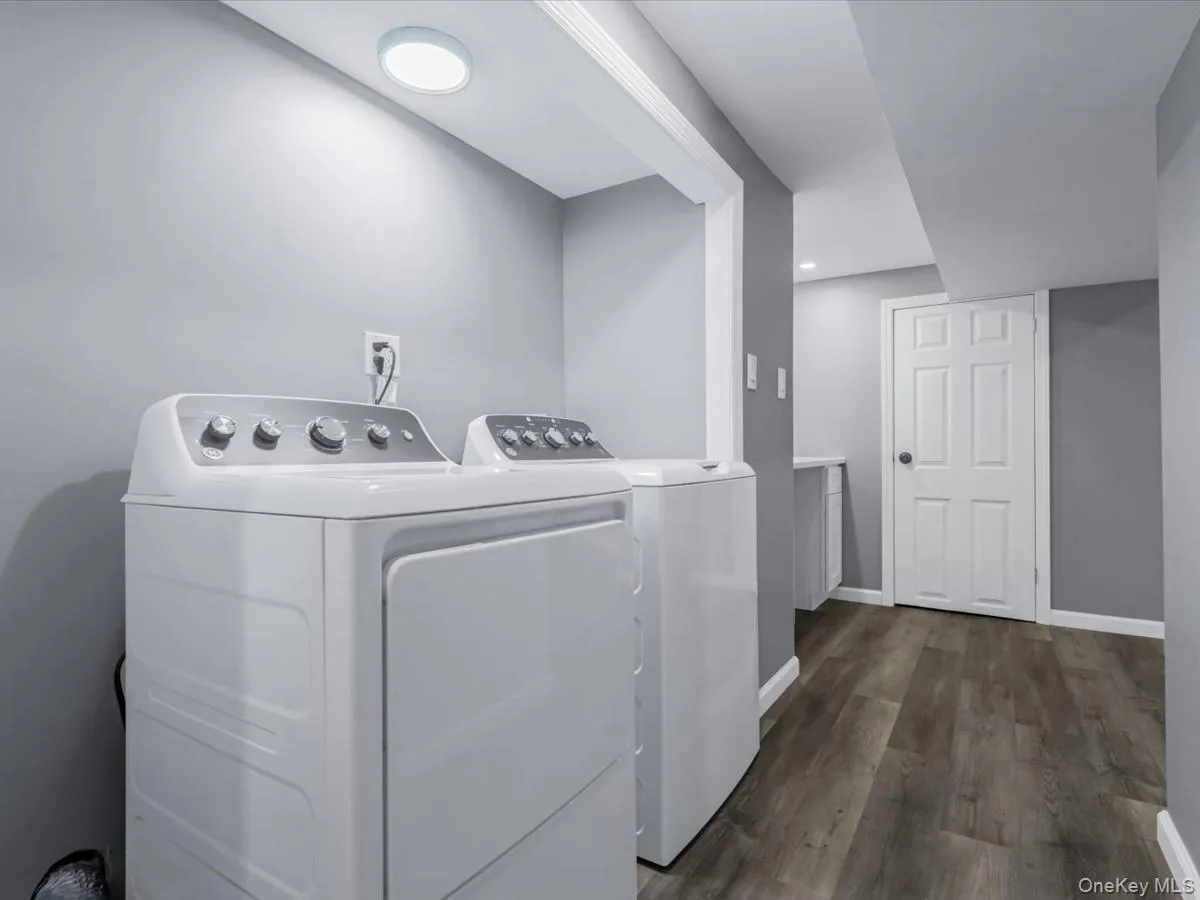 Laundry room with washing machine and dryer and dark wood finished floors Laundry room with washing machine and dryer and dark wood finished floors