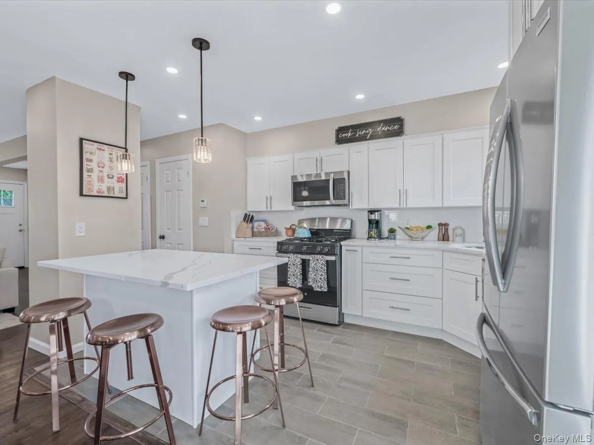 Kitchen with appliances with stainless steel finishes, a kitchen breakfast bar, white cabinetry, hanging light fixtures, and recessed lighting Kitchen with appliances with stainless steel finishes, a kitchen breakfast bar, white cabinetry, hanging light fixtures, and recessed lighting