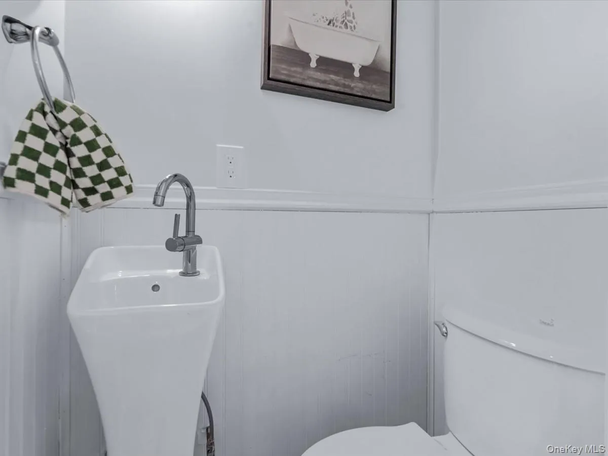 Half bathroom featuring wainscoting and a sink Half bathroom featuring wainscoting and a sink