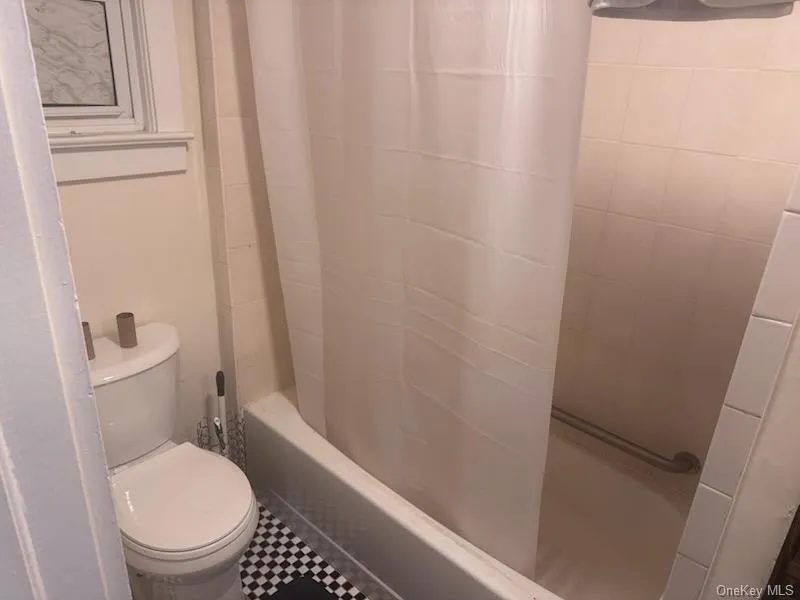 Bathroom featuring shower / bath combination with curtain and tile patterned floors Bathroom featuring shower / bath combination with curtain and tile patterned floors