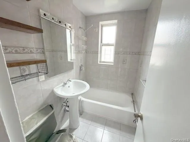 Full bath featuring bathtub / shower combination, light tile patterned floors, and tile walls Full bath featuring bathtub / shower combination, light tile patterned floors, and tile walls