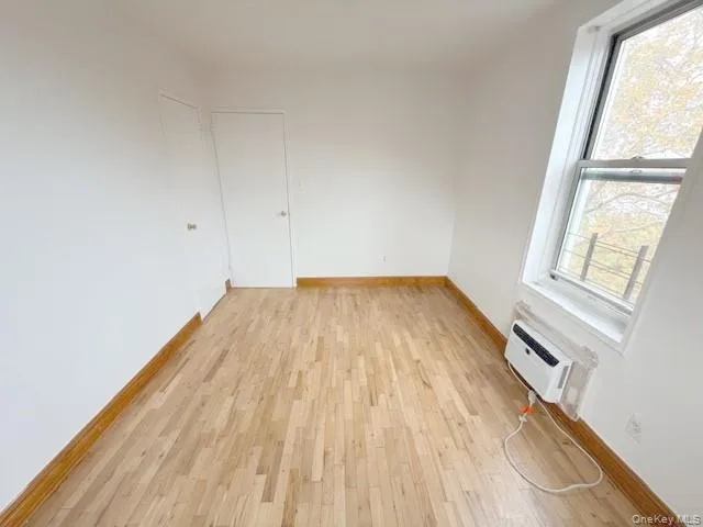 Spare room with light wood finished floors and a wall mounted AC Spare room with light wood finished floors and a wall mounted AC