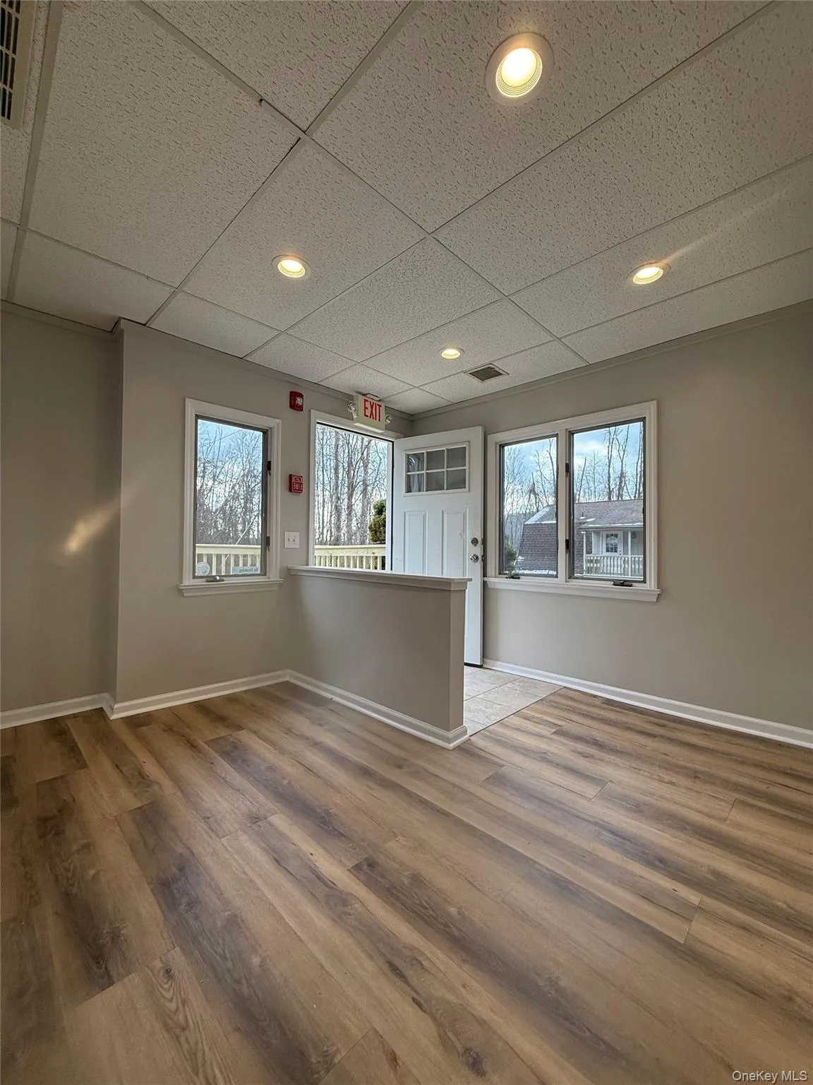 Empty room with a paneled ceiling, light wood-style floors, healthy amount of natural light, and recessed lighting Empty room with a paneled ceiling, light wood-style floors, healthy amount of natural light, and recessed lighting