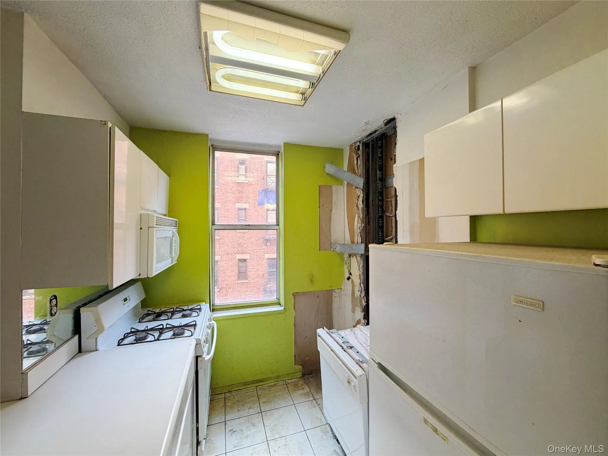Kitchen with white appliances, white cabinetry, light countertops, and a textured ceiling Kitchen with white appliances, white cabinetry, light countertops, and a textured ceiling