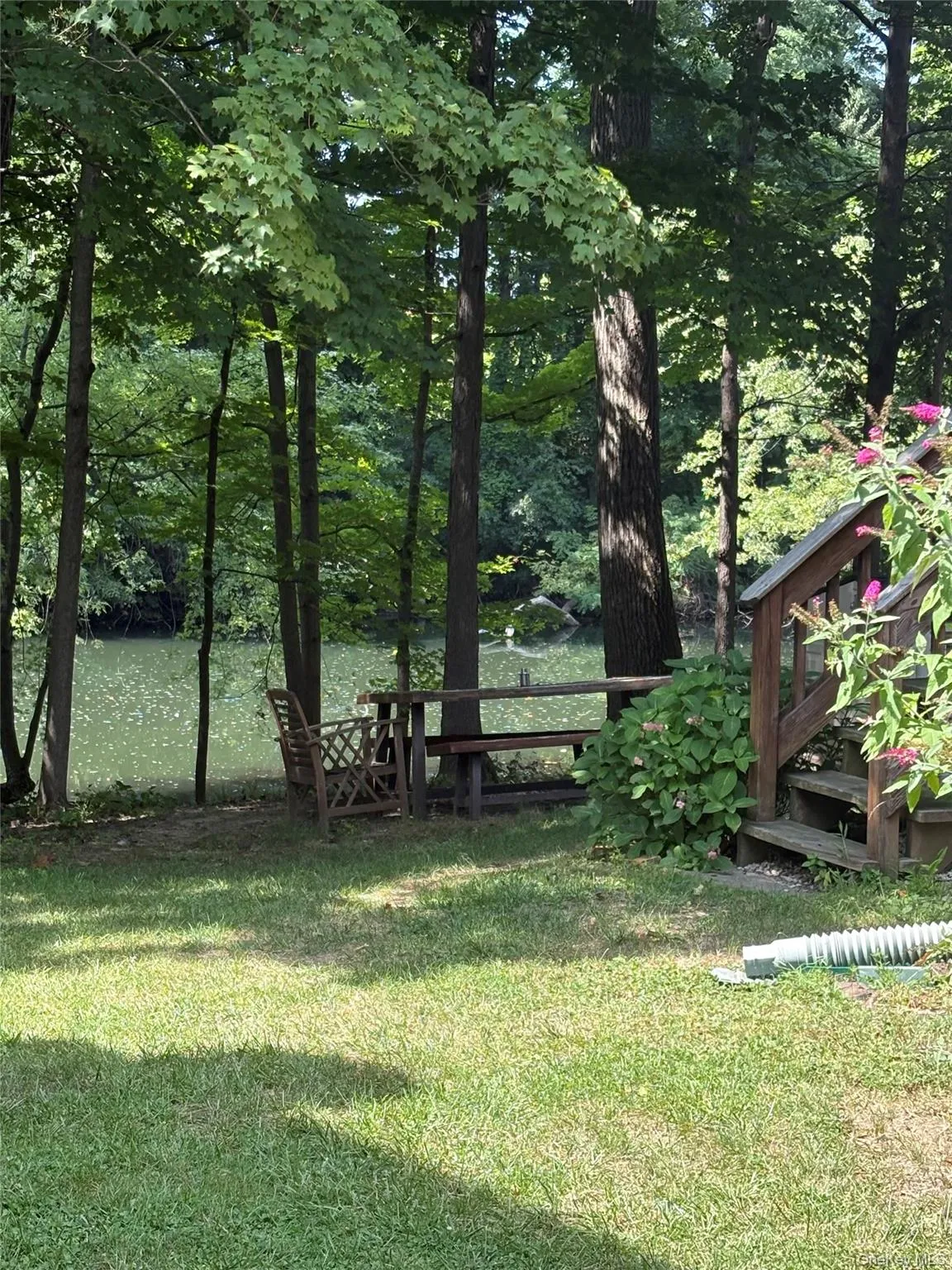 View of grassy yard featuring a deck with water view View of grassy yard featuring a deck with water view