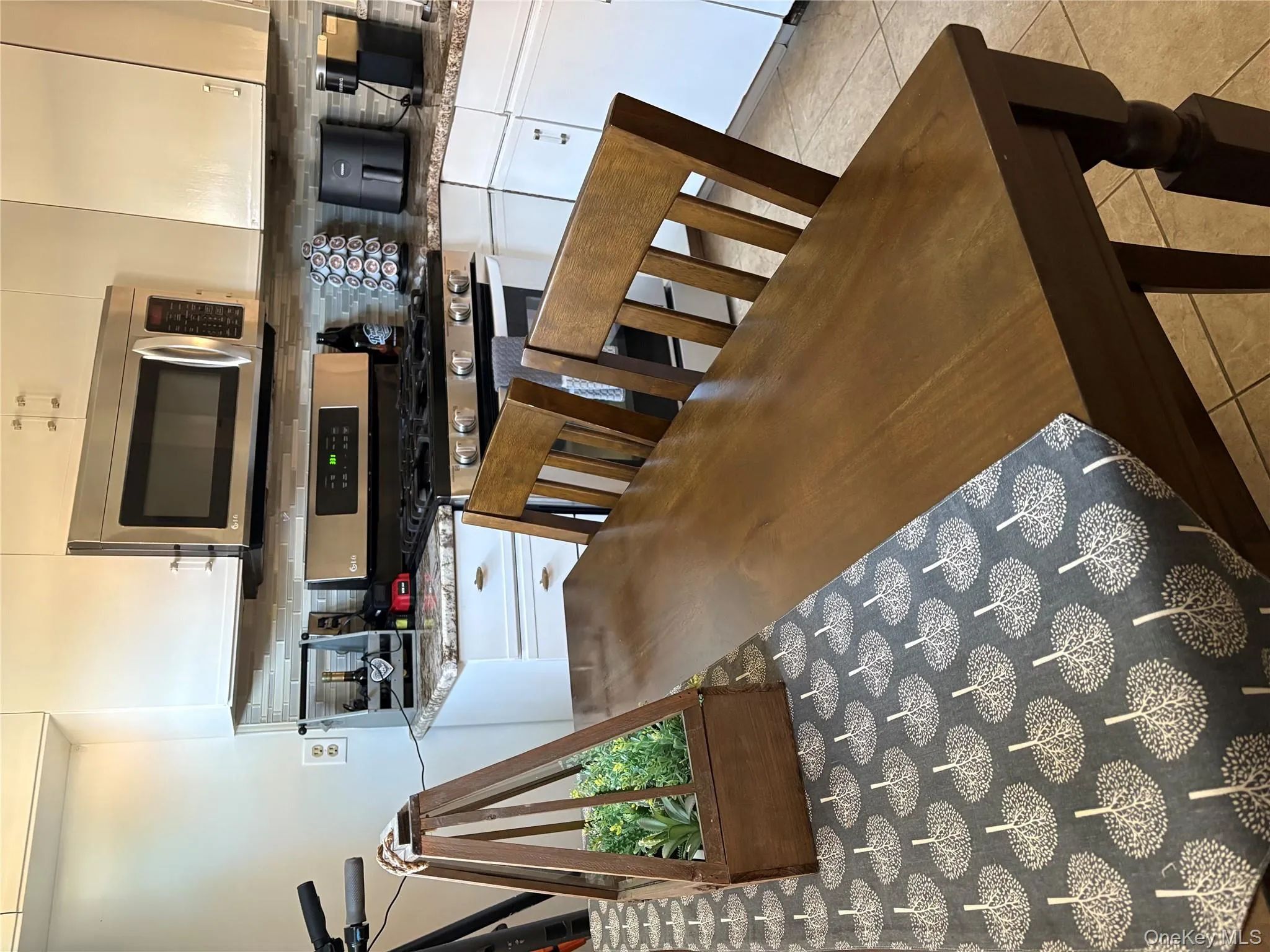 Kitchen featuring stove, white microwave, tasteful backsplash, and white cabinets Kitchen featuring stove, white microwave, tasteful backsplash, and white cabinets