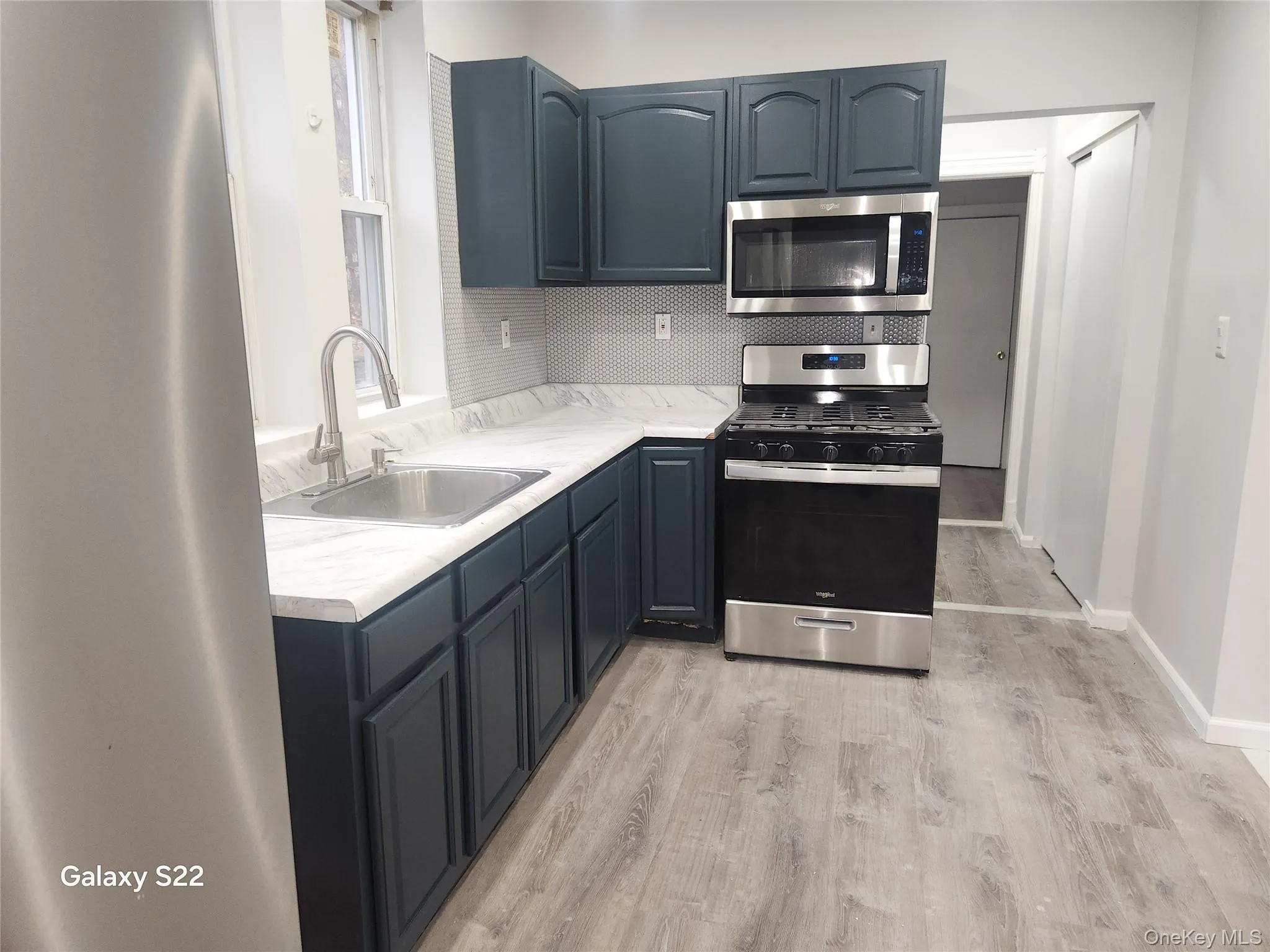 Kitchen featuring stainless steel appliances, light countertops, light wood-style flooring, and decorative backsplash Kitchen featuring stainless steel appliances, light countertops, light wood-style flooring, and decorative backsplash