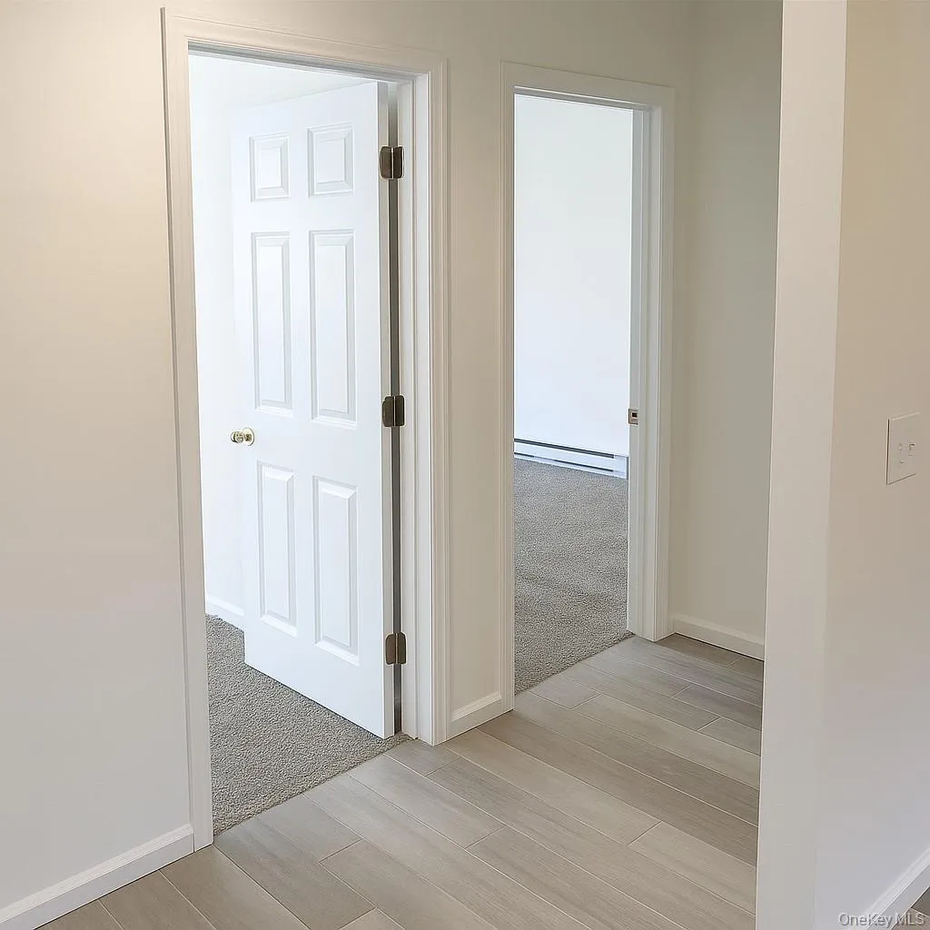 Corridor featuring wood finish floors and a baseboard radiator Corridor featuring wood finish floors and a baseboard radiator