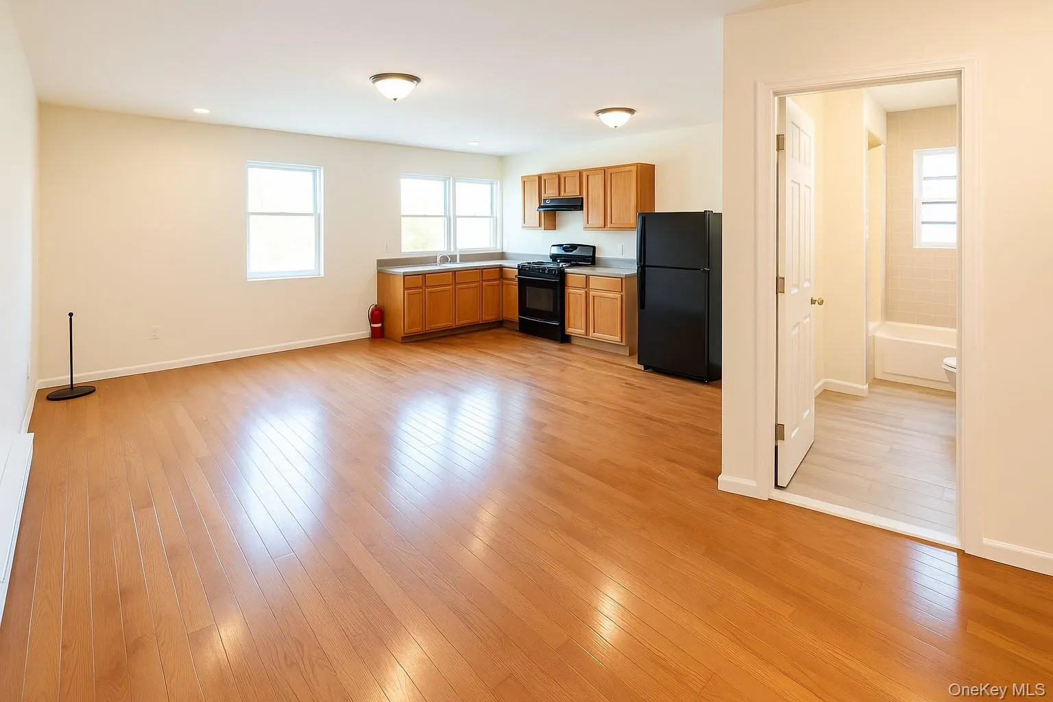 Kitchen with black appliances, light countertops, light wood-style flooring, brown cabinets, and under cabinet range hood Kitchen with black appliances, light countertops, light wood-style flooring, brown cabinets, and under cabinet range hood