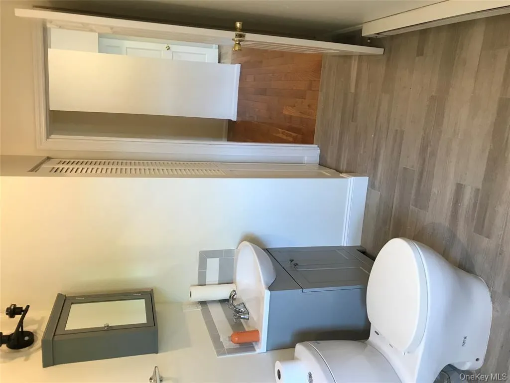 Half bathroom featuring light wood-type flooring, vanity, and baseboard heating Half bathroom featuring light wood-type flooring, vanity, and baseboard heating