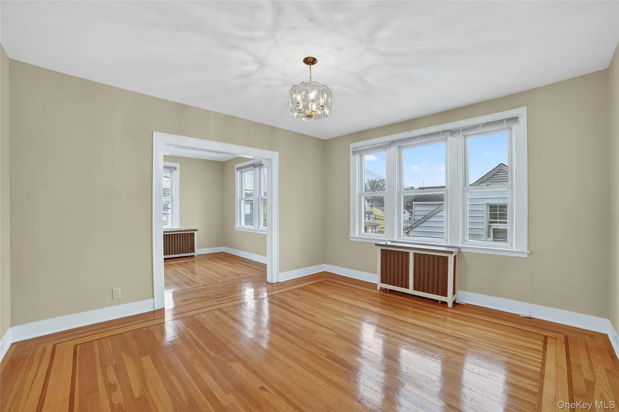 Dining room featuring light wood-style flooring, radiator heating unit, and a chandelier Dining room featuring light wood-style flooring, radiator heating unit, and a chandelier