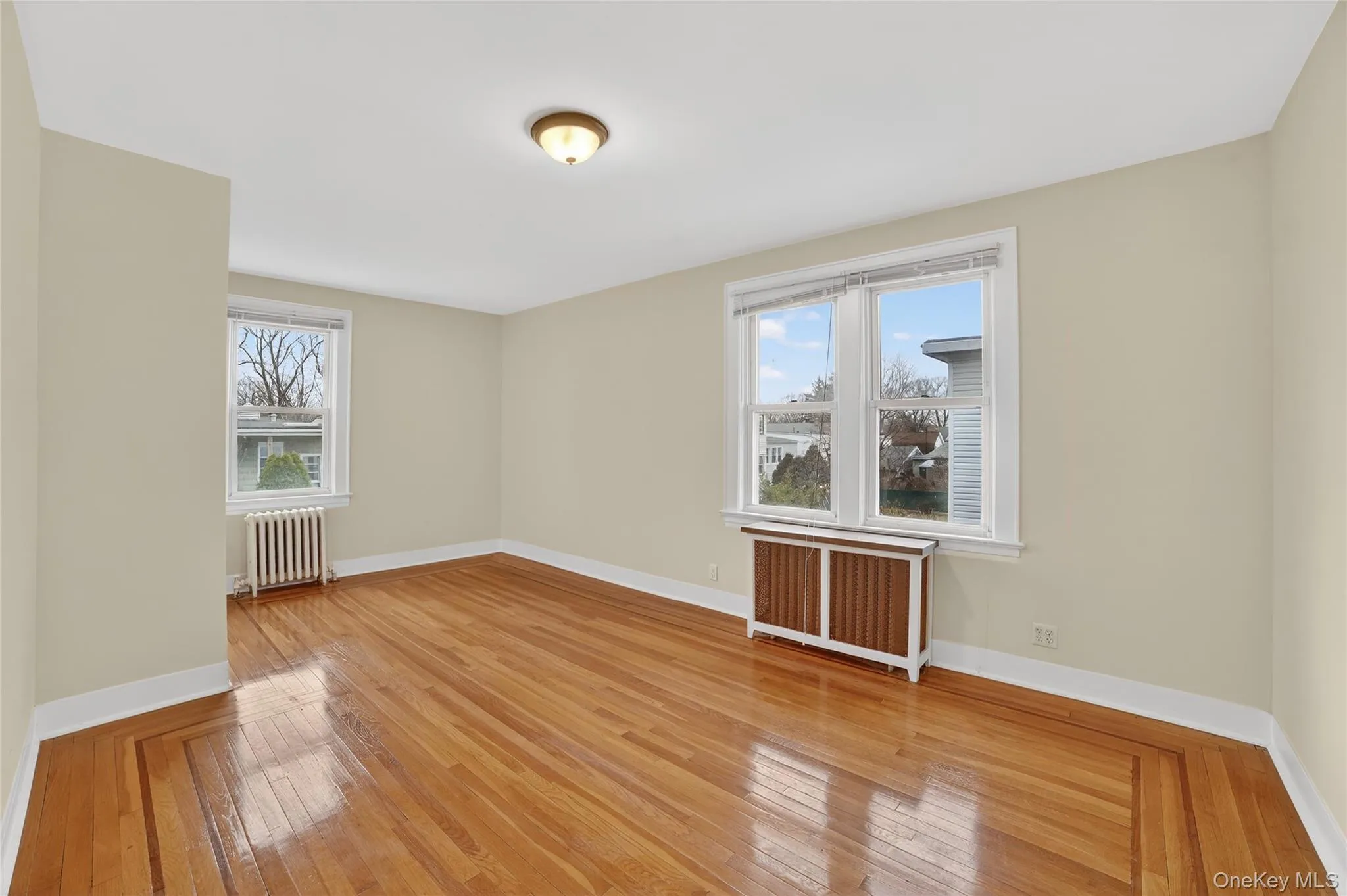 Main bedroom featuring radiator, light wood-style floors, and healthy amount of natural light Main bedroom featuring radiator, light wood-style floors, and healthy amount of natural light