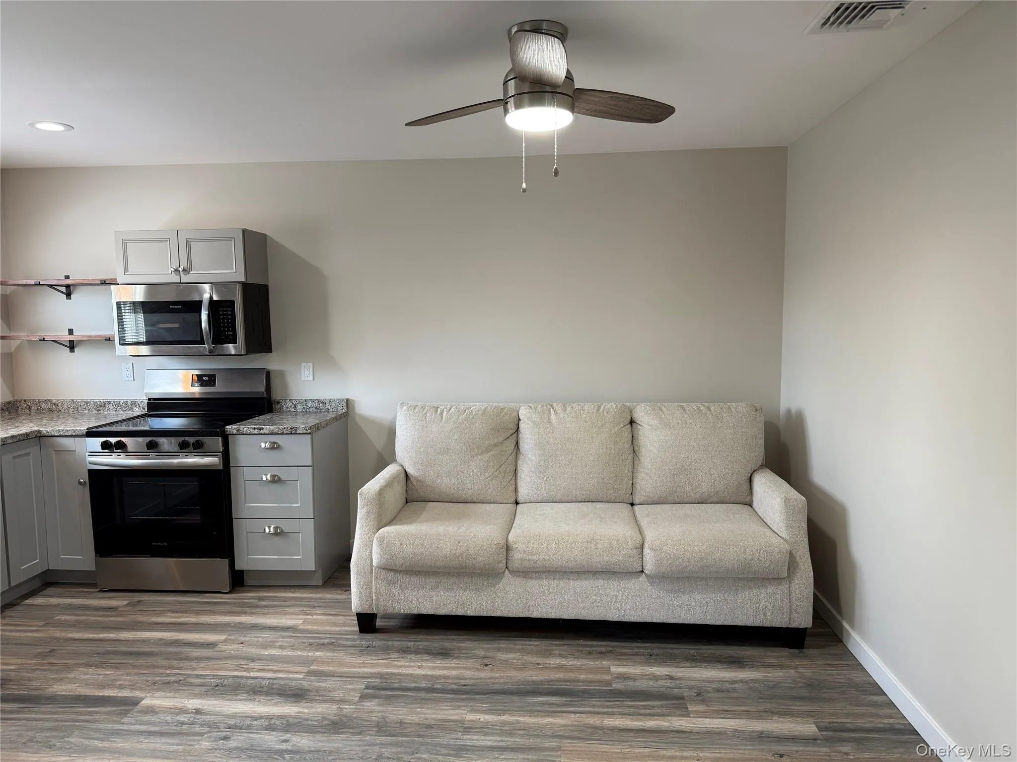 Living area with dark wood-style floors and ceiling fan Living area with dark wood-style floors and ceiling fan