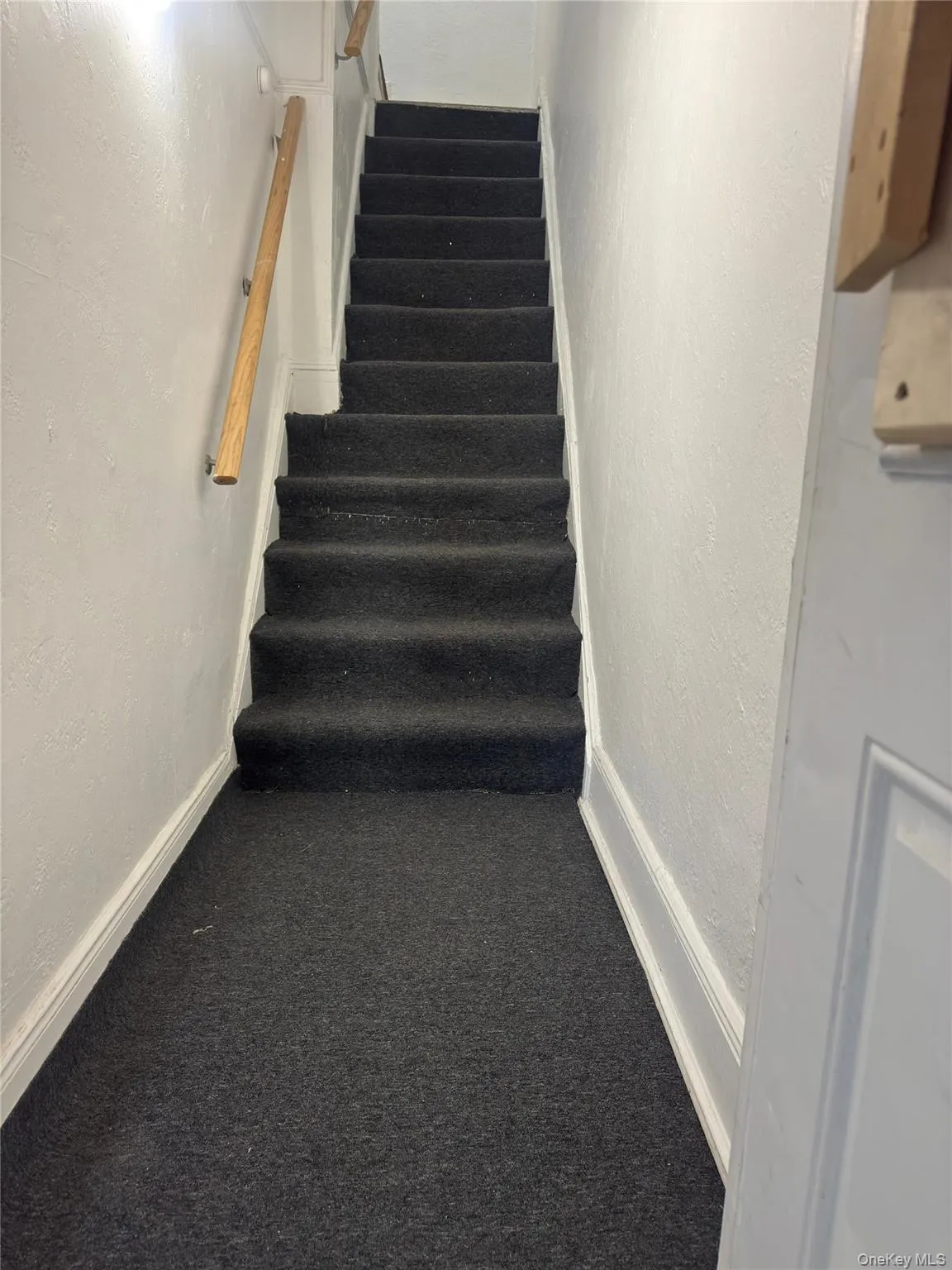 Stairway featuring a textured wall and carpet flooring Stairway featuring a textured wall and carpet flooring