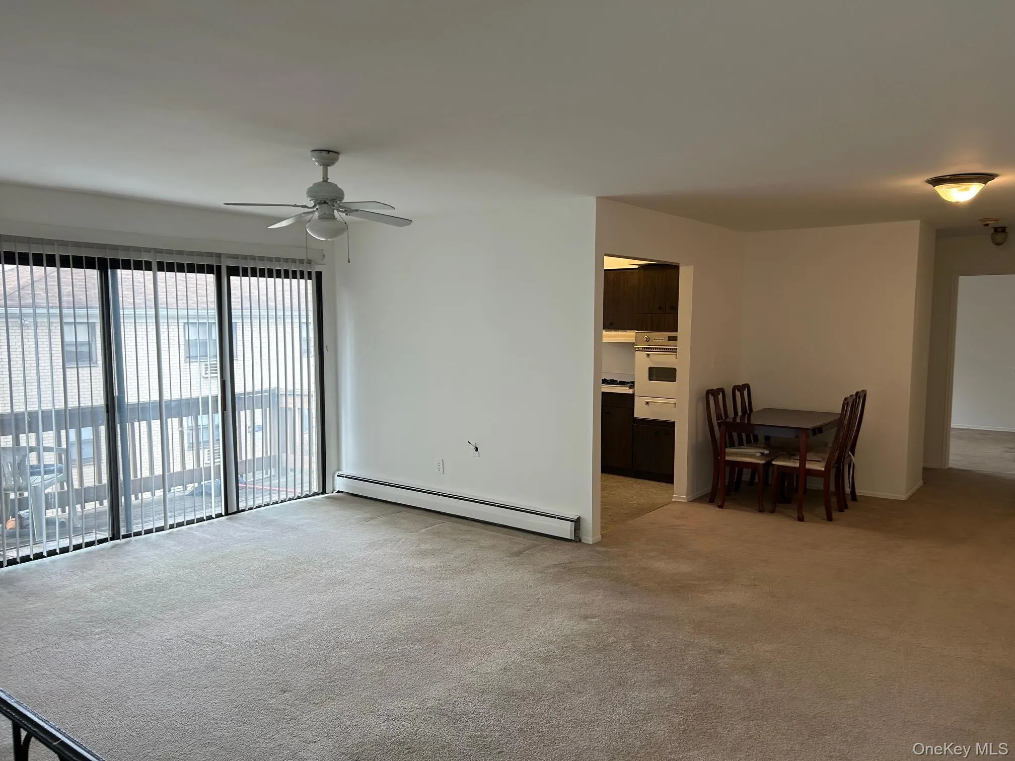 Unfurnished living room featuring a baseboard radiator, light colored carpet, and a ceiling fan Unfurnished living room featuring a baseboard radiator, light colored carpet, and a ceiling fan
