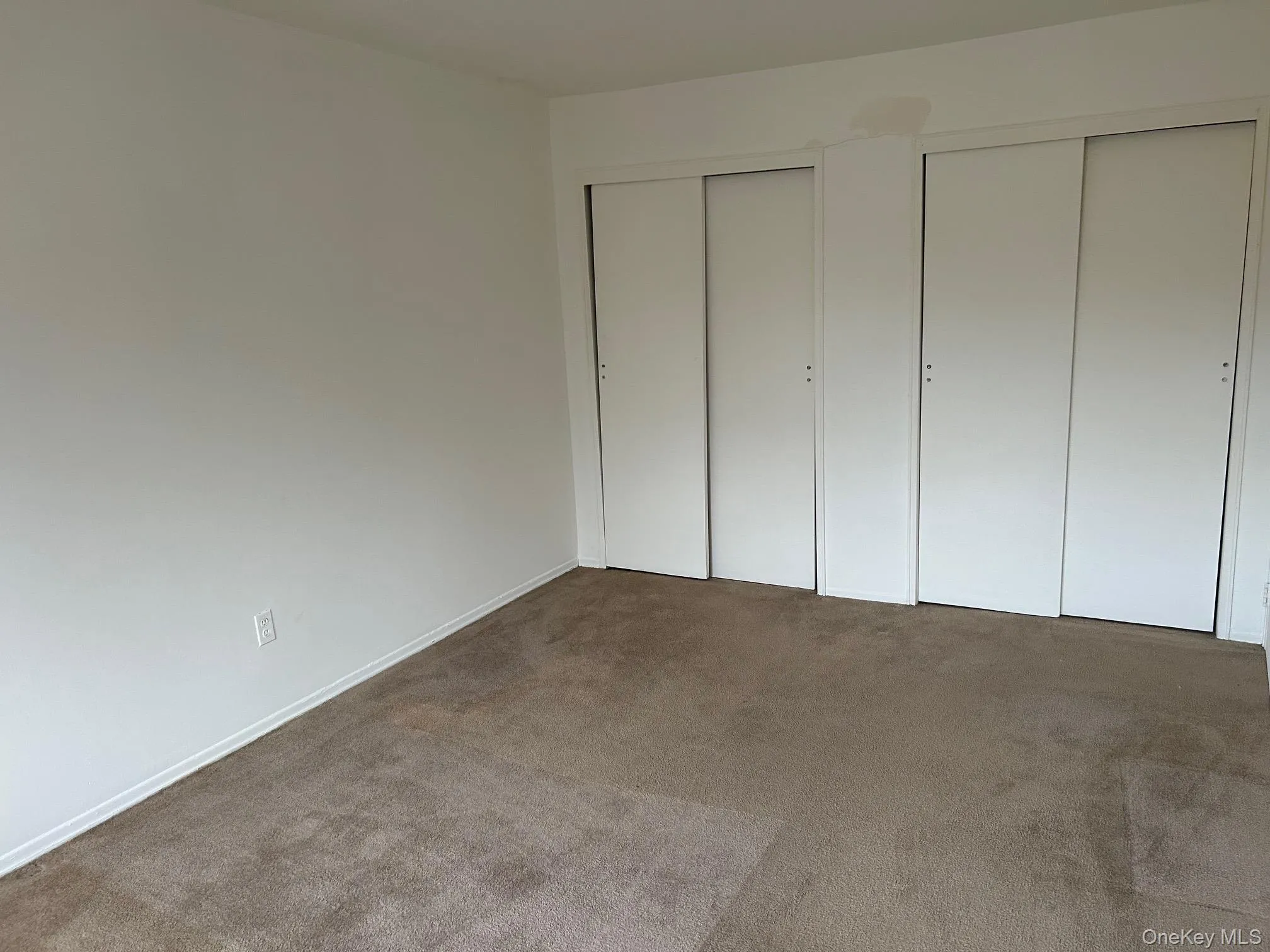 Unfurnished bedroom featuring two closets and carpet floors Unfurnished bedroom featuring two closets and carpet floors
