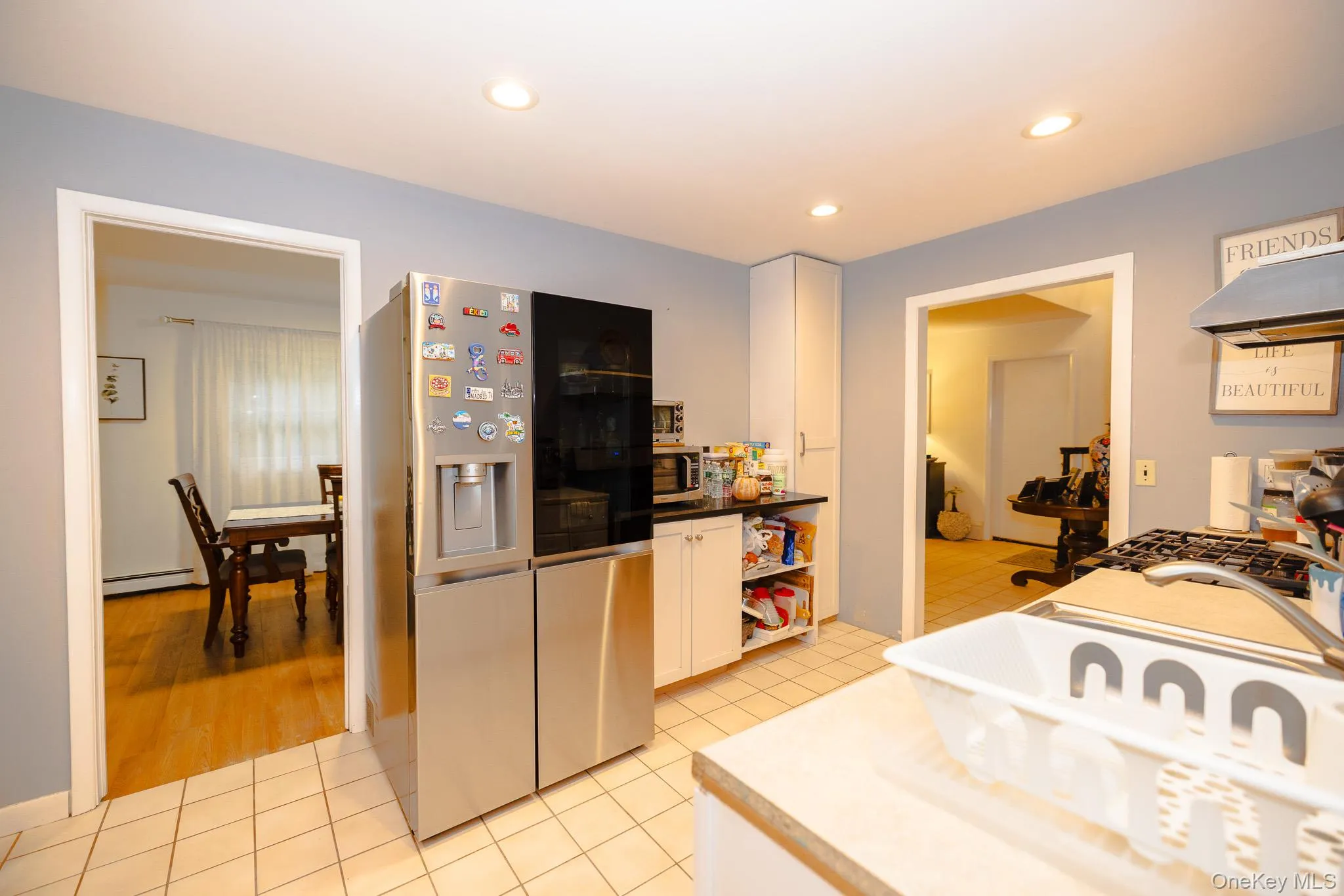 Kitchen with stainless steel appliances, white cabinets, light tile patterned floors, dark countertops, and recessed lighting Kitchen with stainless steel appliances, white cabinets, light tile patterned floors, dark countertops, and recessed lighting