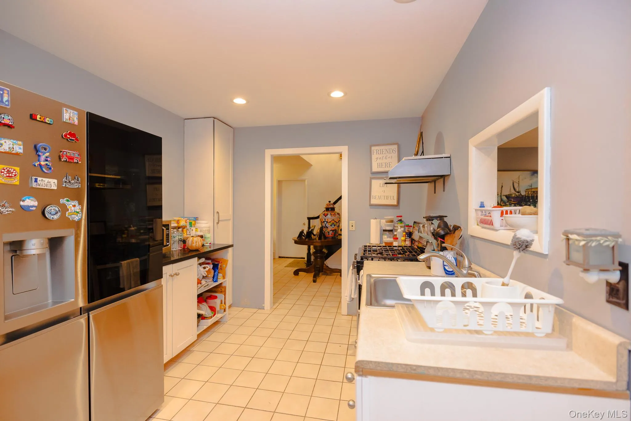 Kitchen with stainless steel appliances, white cabinets, light tile patterned flooring, open shelves, and exhaust hood Kitchen with stainless steel appliances, white cabinets, light tile patterned flooring, open shelves, and exhaust hood