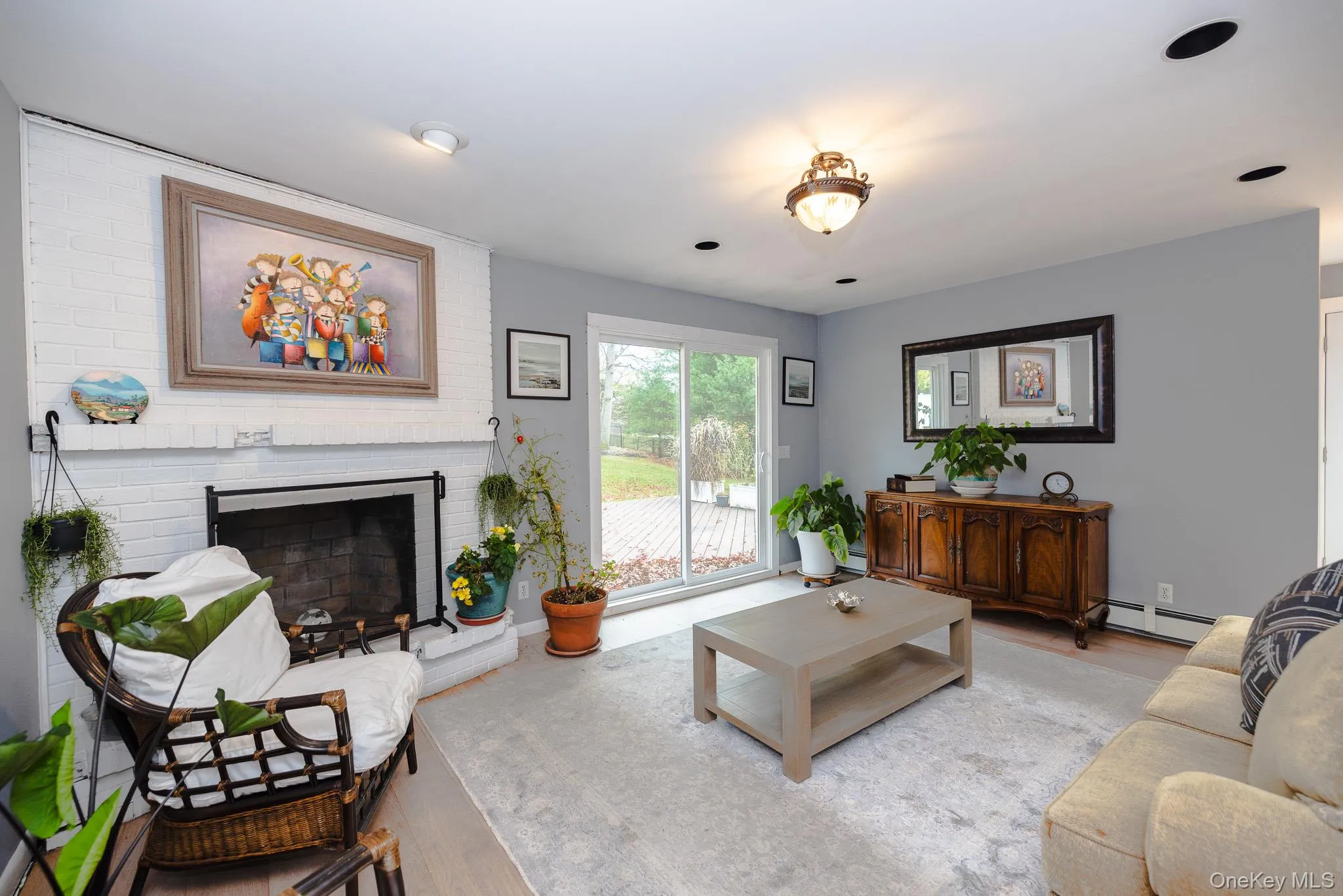 Living area featuring a brick fireplace, wood finished floors, and a baseboard radiator Living area featuring a brick fireplace, wood finished floors, and a baseboard radiator