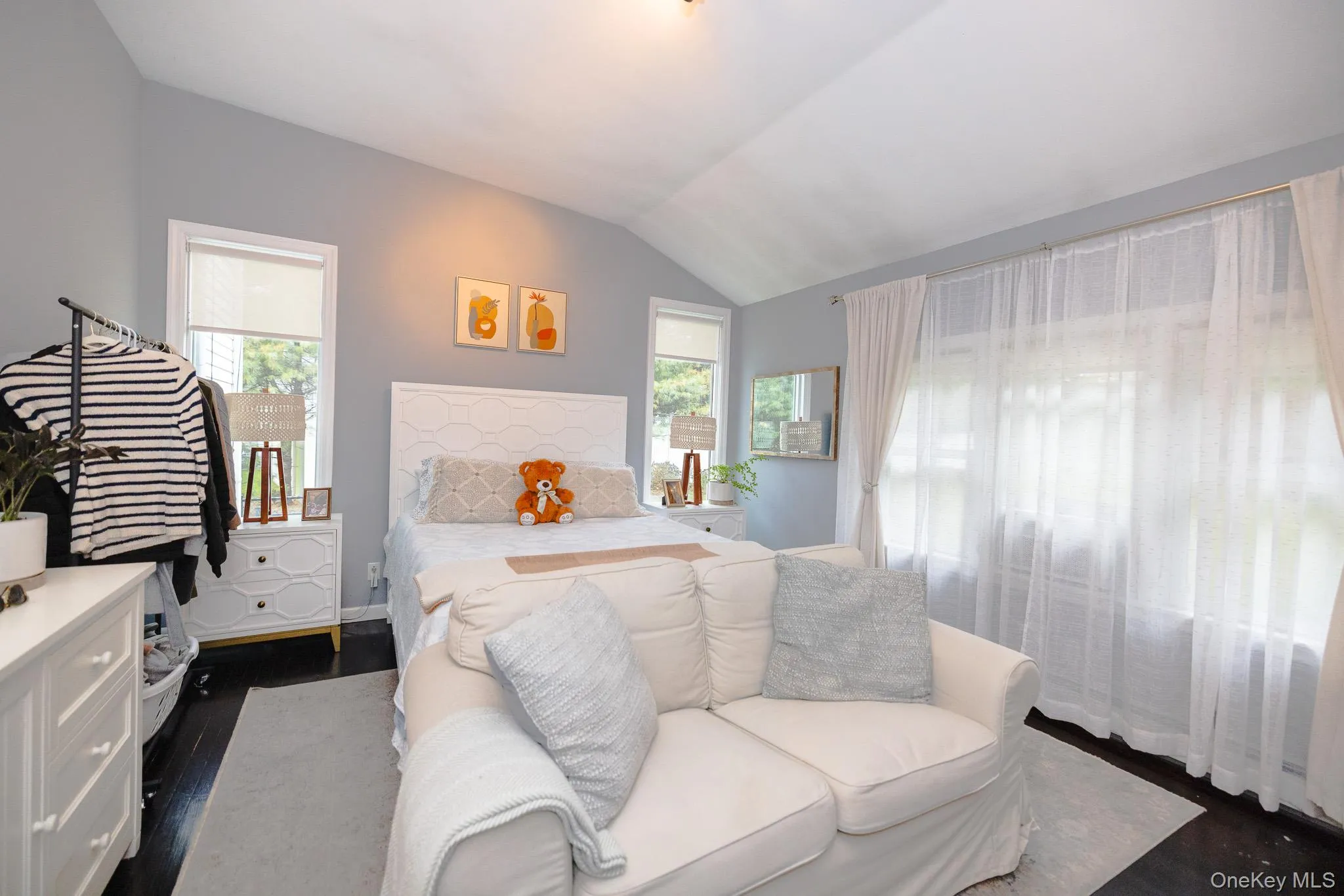 Bedroom featuring vaulted ceiling, multiple windows, and dark wood-style flooring Bedroom featuring vaulted ceiling, multiple windows, and dark wood-style flooring