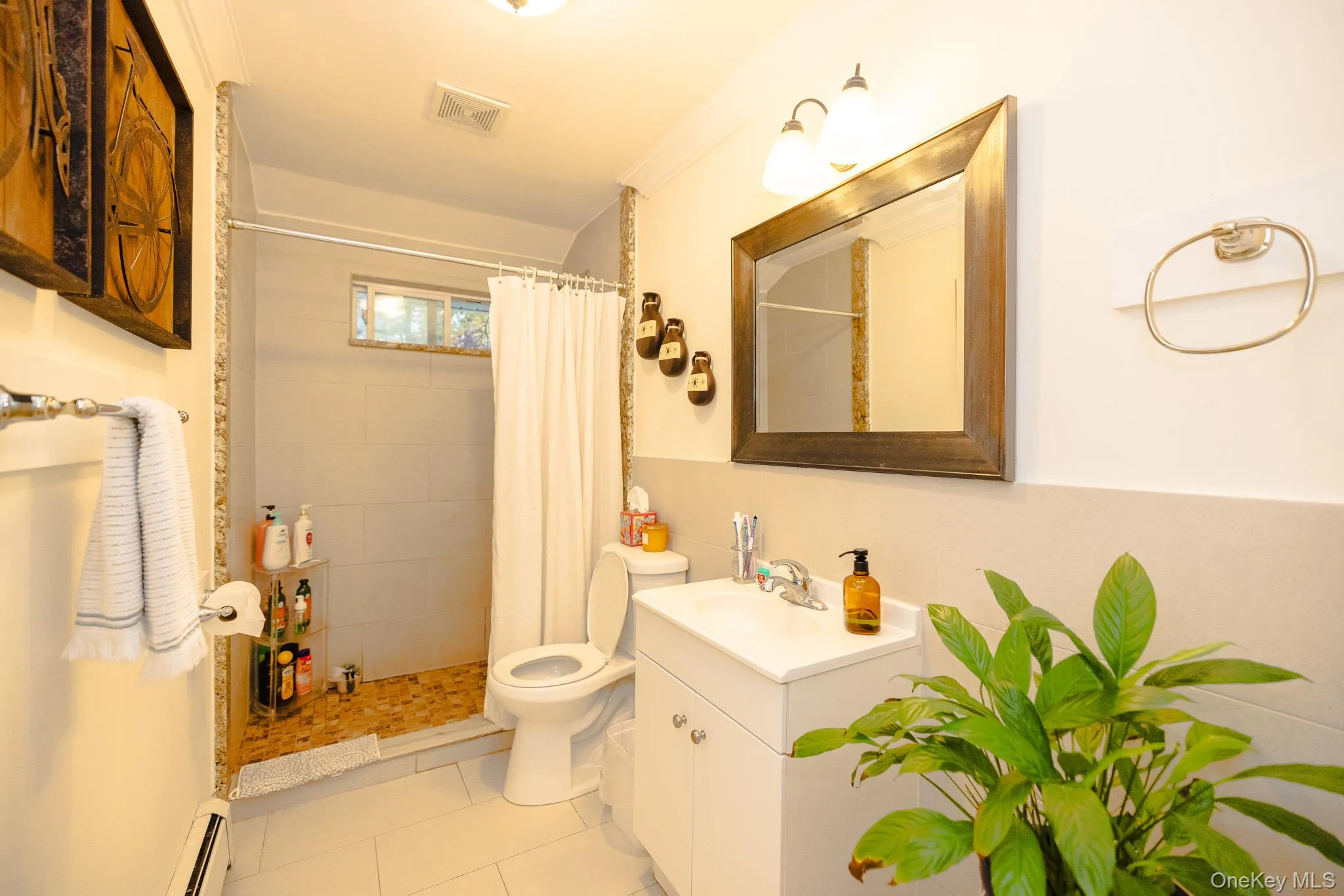 Bathroom with vanity, a shower stall, light tile patterned floors, and a baseboard heating unit Bathroom with vanity, a shower stall, light tile patterned floors, and a baseboard heating unit