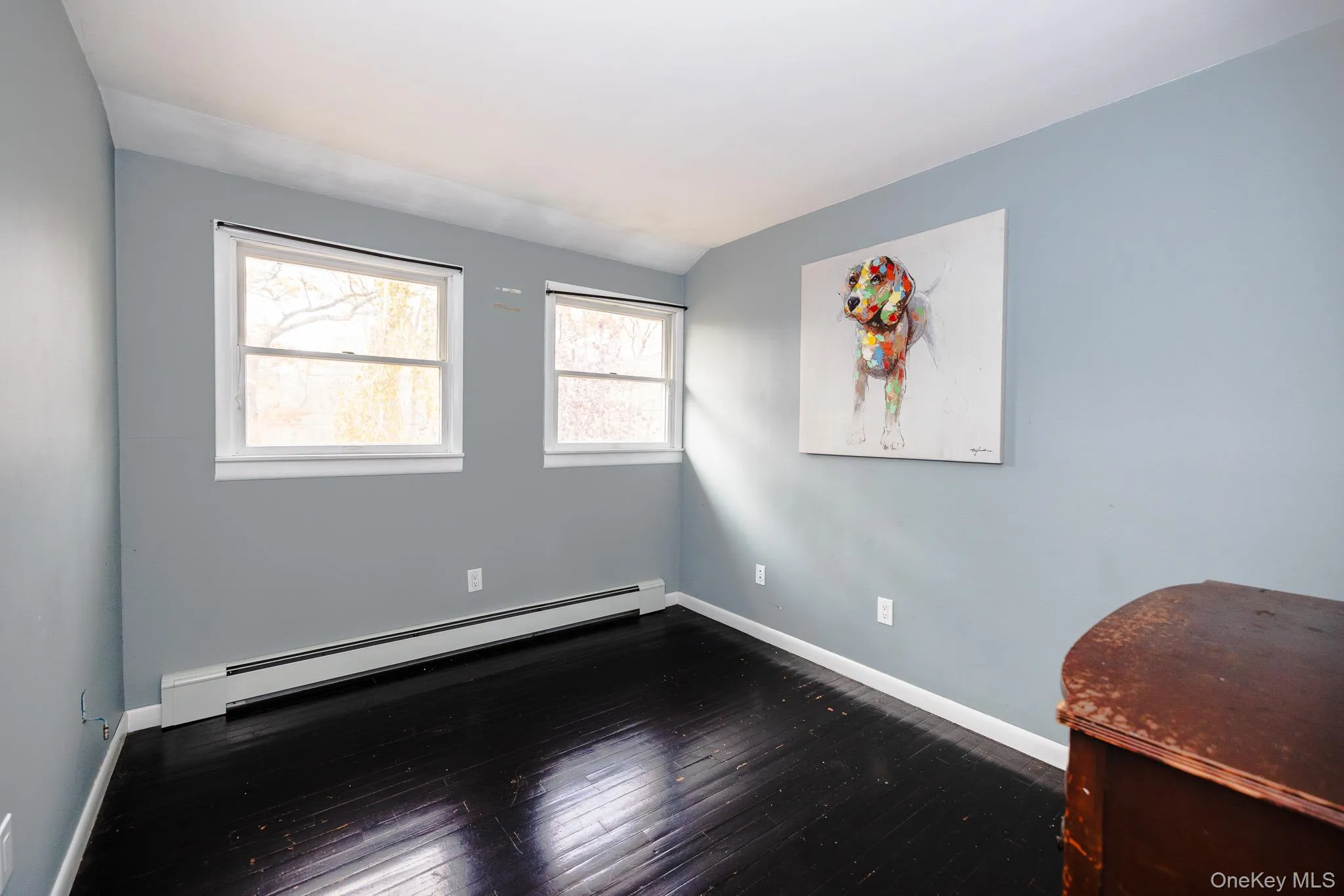 Empty room with a baseboard radiator and dark wood finished floors Empty room with a baseboard radiator and dark wood finished floors