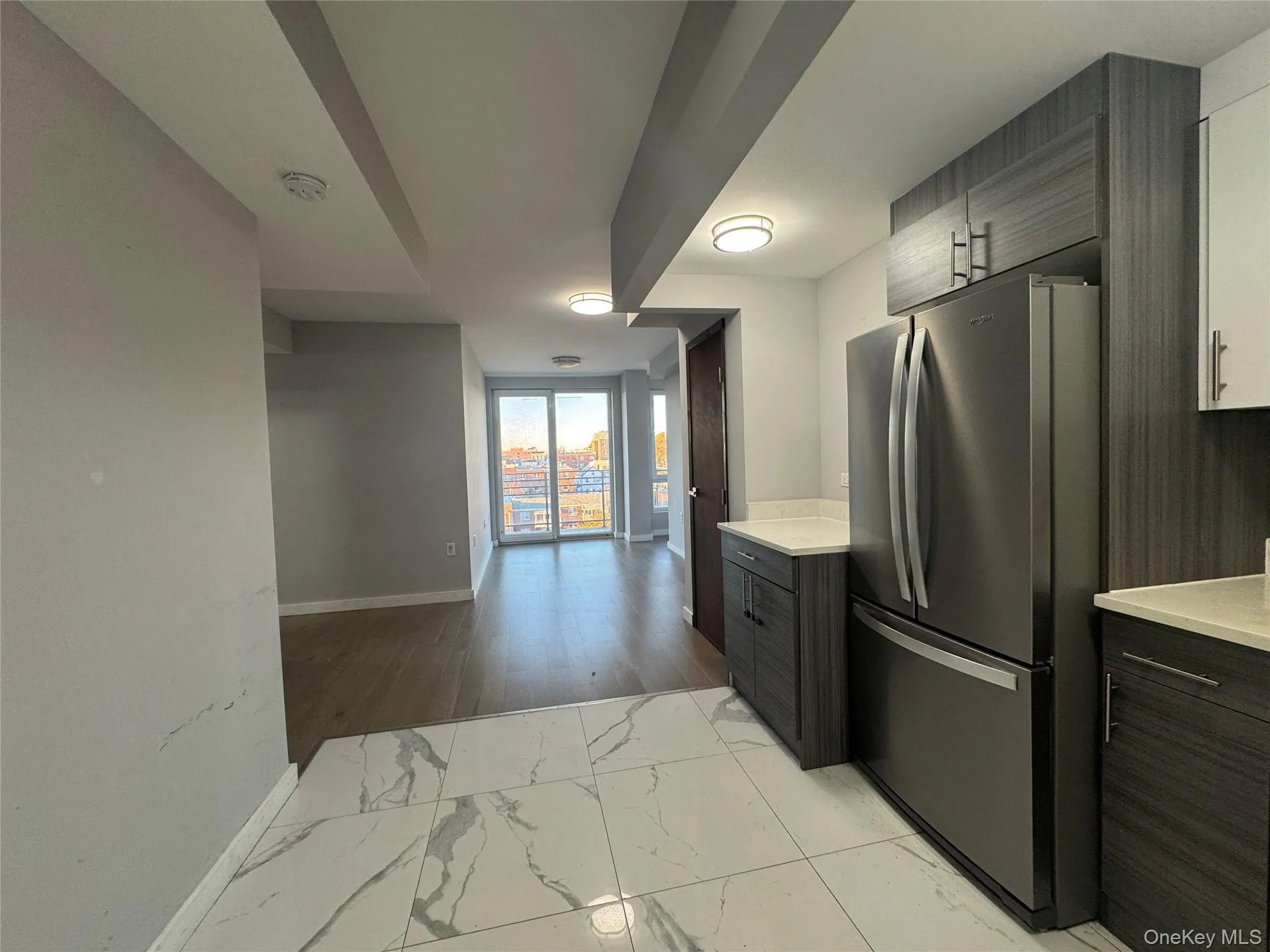 Kitchen featuring light marble finish flooring, freestanding refrigerator, modern cabinets, and open floor plan Kitchen featuring light marble finish flooring, freestanding refrigerator, modern cabinets, and open floor plan