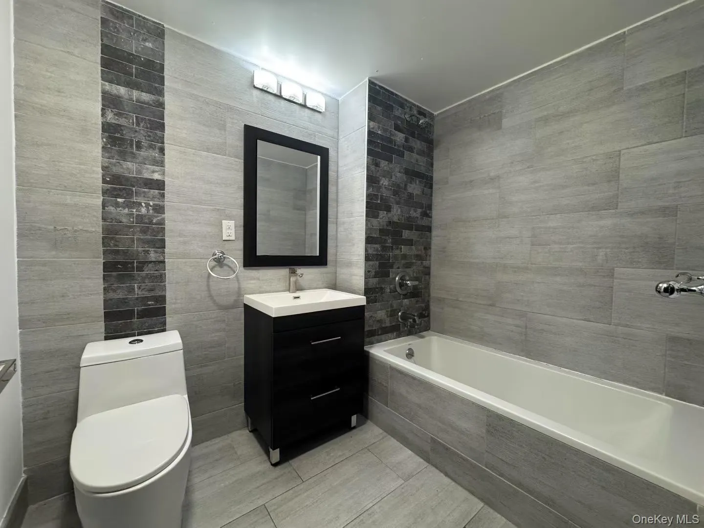 Bathroom featuring vanity, tile walls, and tiled shower / bath Bathroom featuring vanity, tile walls, and tiled shower / bath