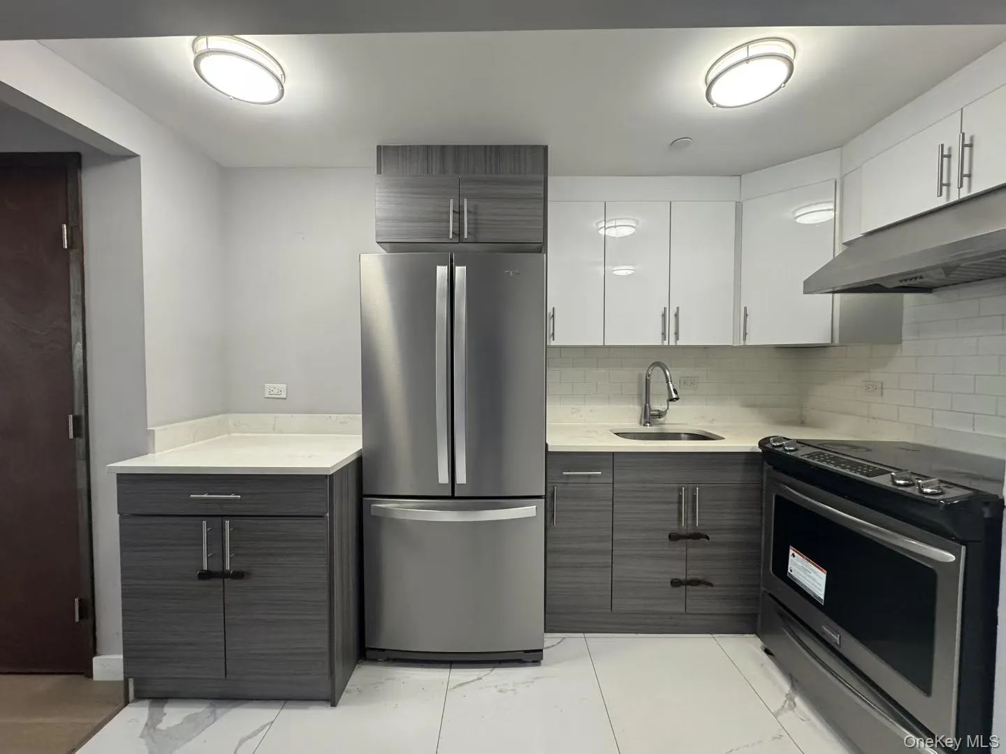 Kitchen featuring appliances with stainless steel finishes, white cabinetry, under cabinet range hood, and modern cabinets Kitchen featuring appliances with stainless steel finishes, white cabinetry, under cabinet range hood, and modern cabinets
