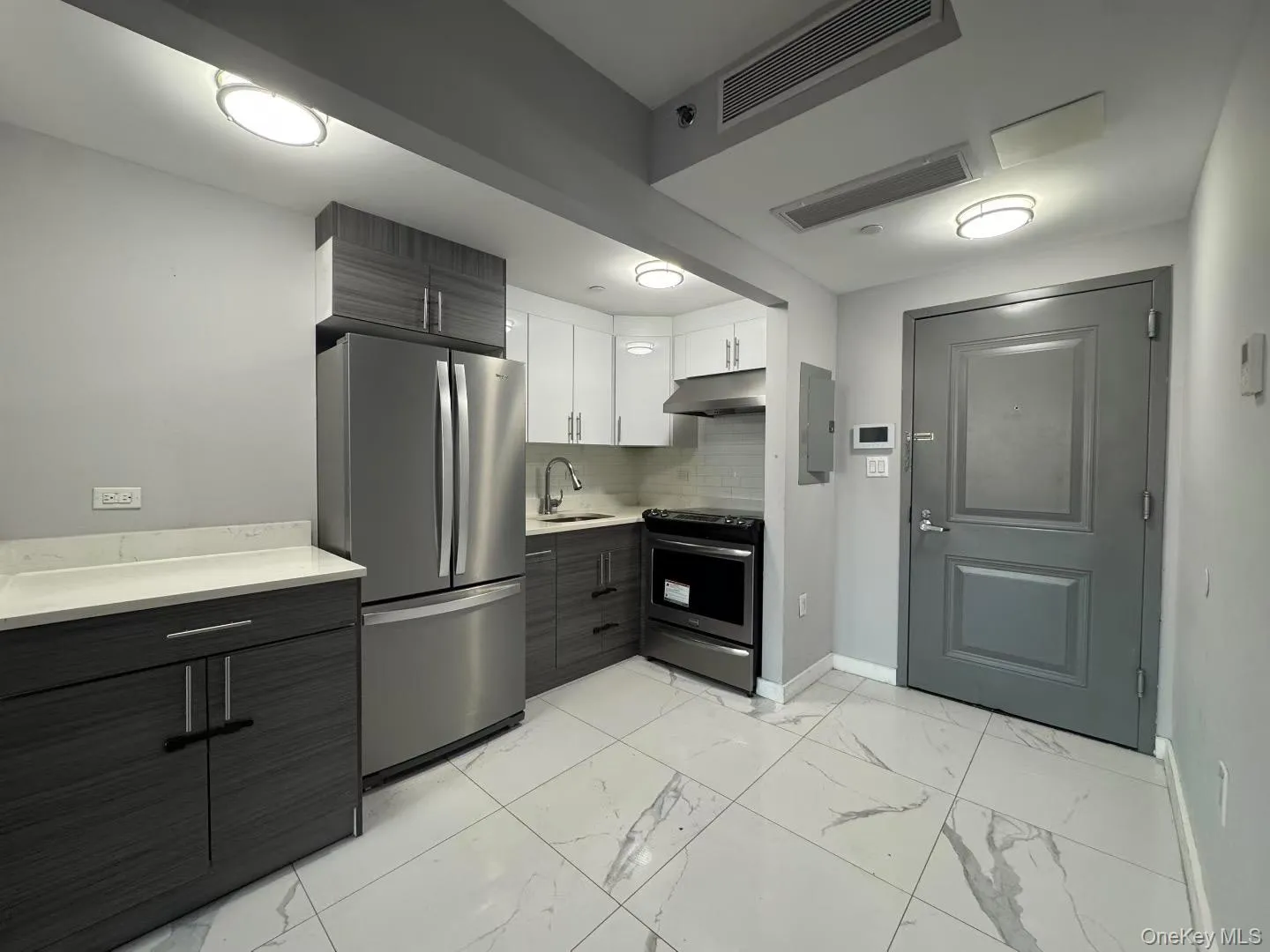 Kitchen with appliances with stainless steel finishes, modern cabinets, white cabinets, and light marble finish floors Kitchen with appliances with stainless steel finishes, modern cabinets, white cabinets, and light marble finish floors