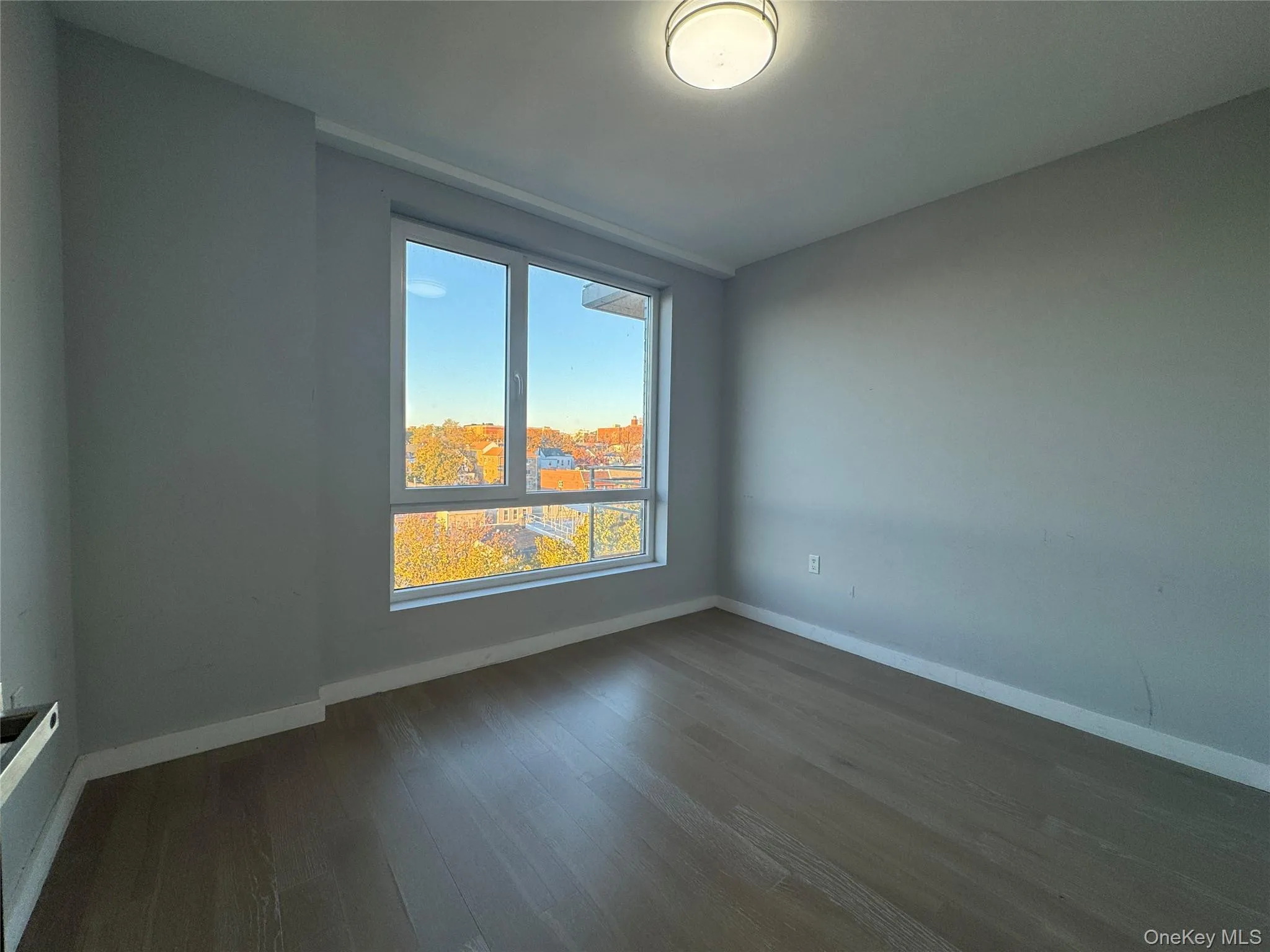 Unfurnished room featuring baseboards and dark wood-style flooring Unfurnished room featuring baseboards and dark wood-style flooring
