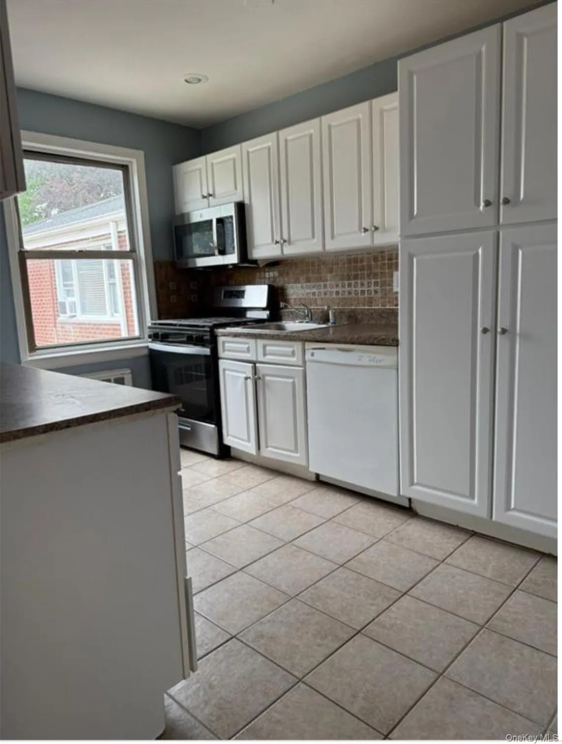 Kitchen featuring dark countertops, appliances with stainless steel finishes, white cabinetry, tasteful backsplash, and recessed lighting Kitchen featuring dark countertops, appliances with stainless steel finishes, white cabinetry, tasteful backsplash, and recessed lighting