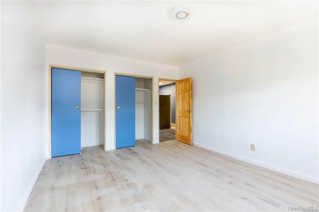 Unfurnished bedroom featuring multiple closets and light wood-style floors Unfurnished bedroom featuring multiple closets and light wood-style floors