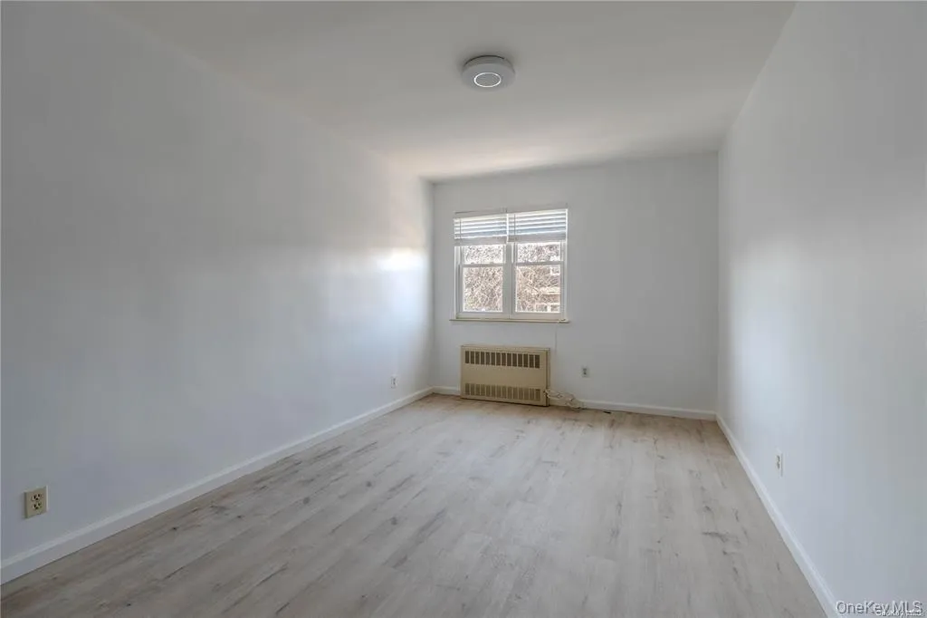 Empty room with light wood finished floors and radiator Empty room with light wood finished floors and radiator